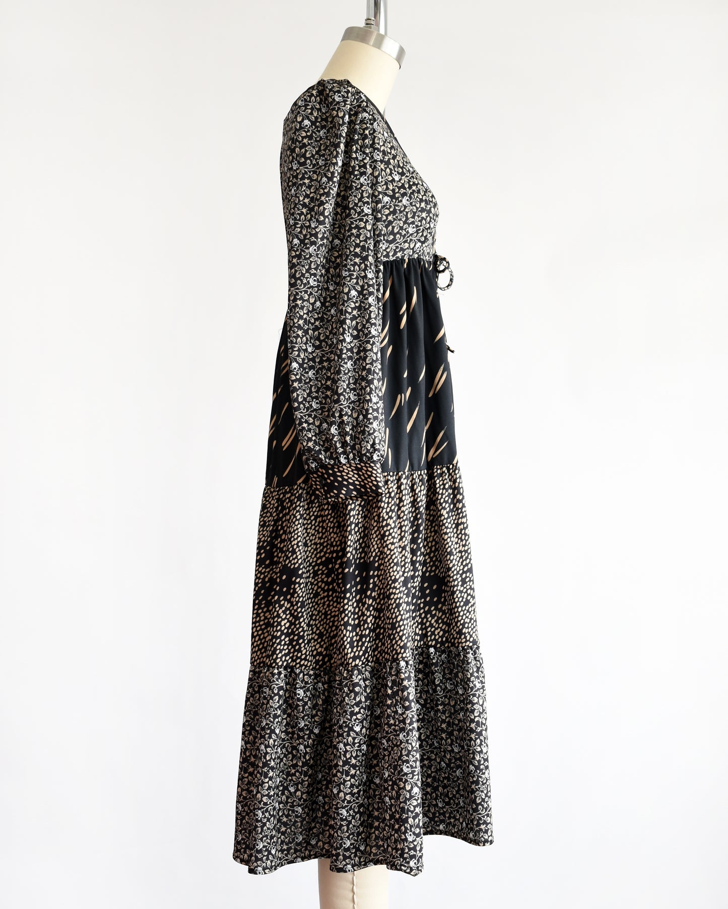 side view of a vintage 1970s black floral dress on a mannequin against a white background