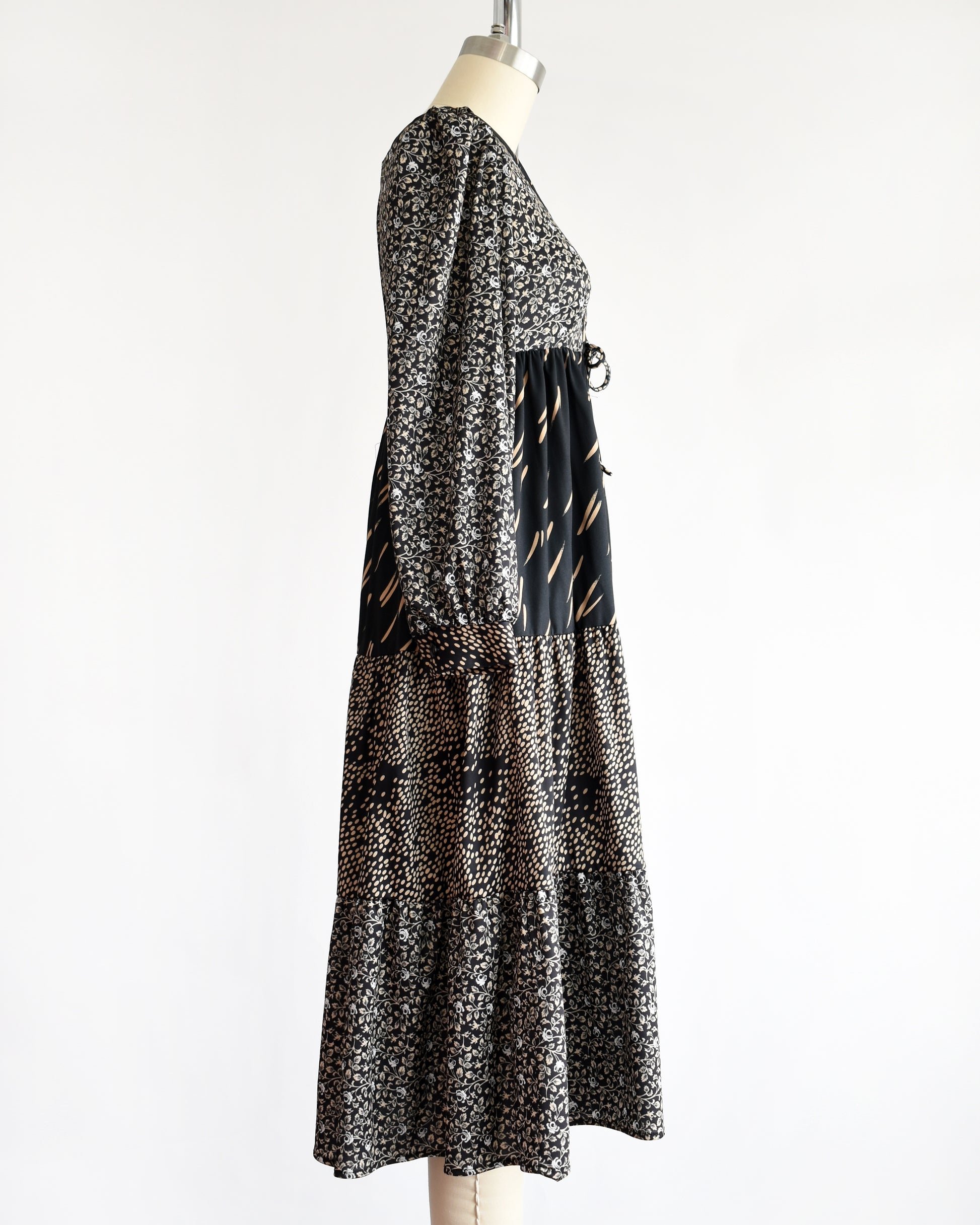 side view of a vintage 1970s black floral dress on a mannequin against a white background