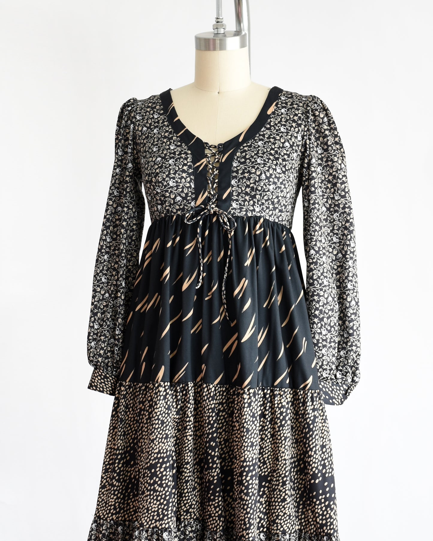side front view of a vintage 1970s black floral dress on a mannequin against a white background