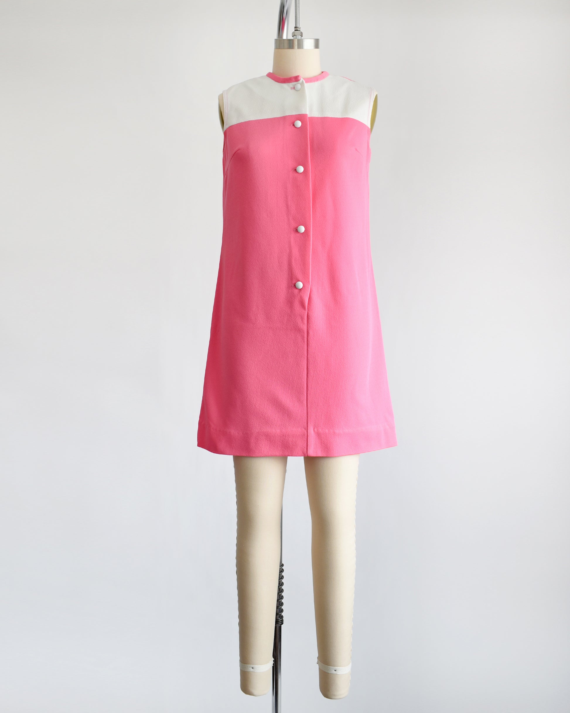 a vintage 1960s pink and white mod mini dress that has five white buttons down the front.