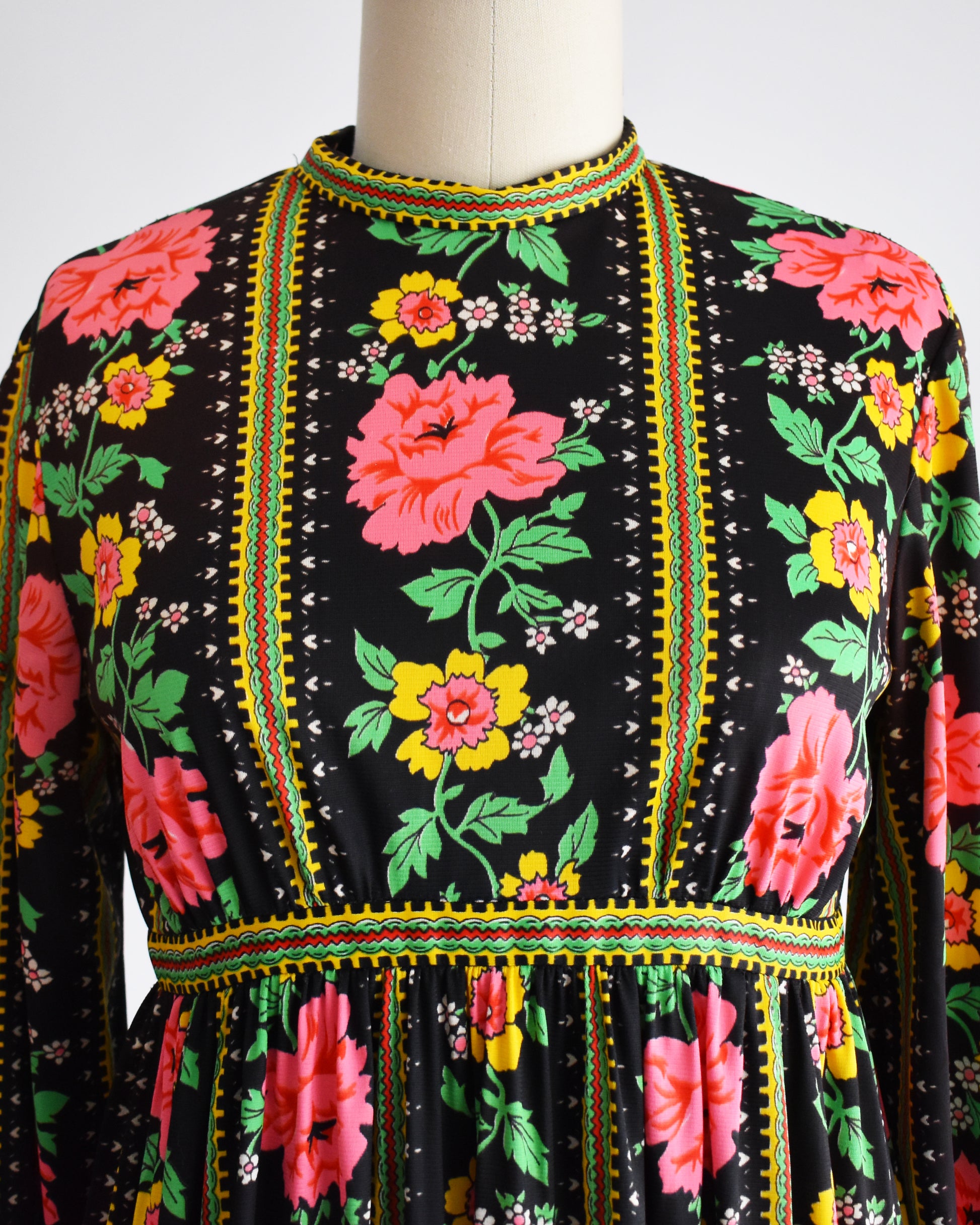 close up of the bodice of a vintage 1960s/1970s floral dress on a mannequin against a white background