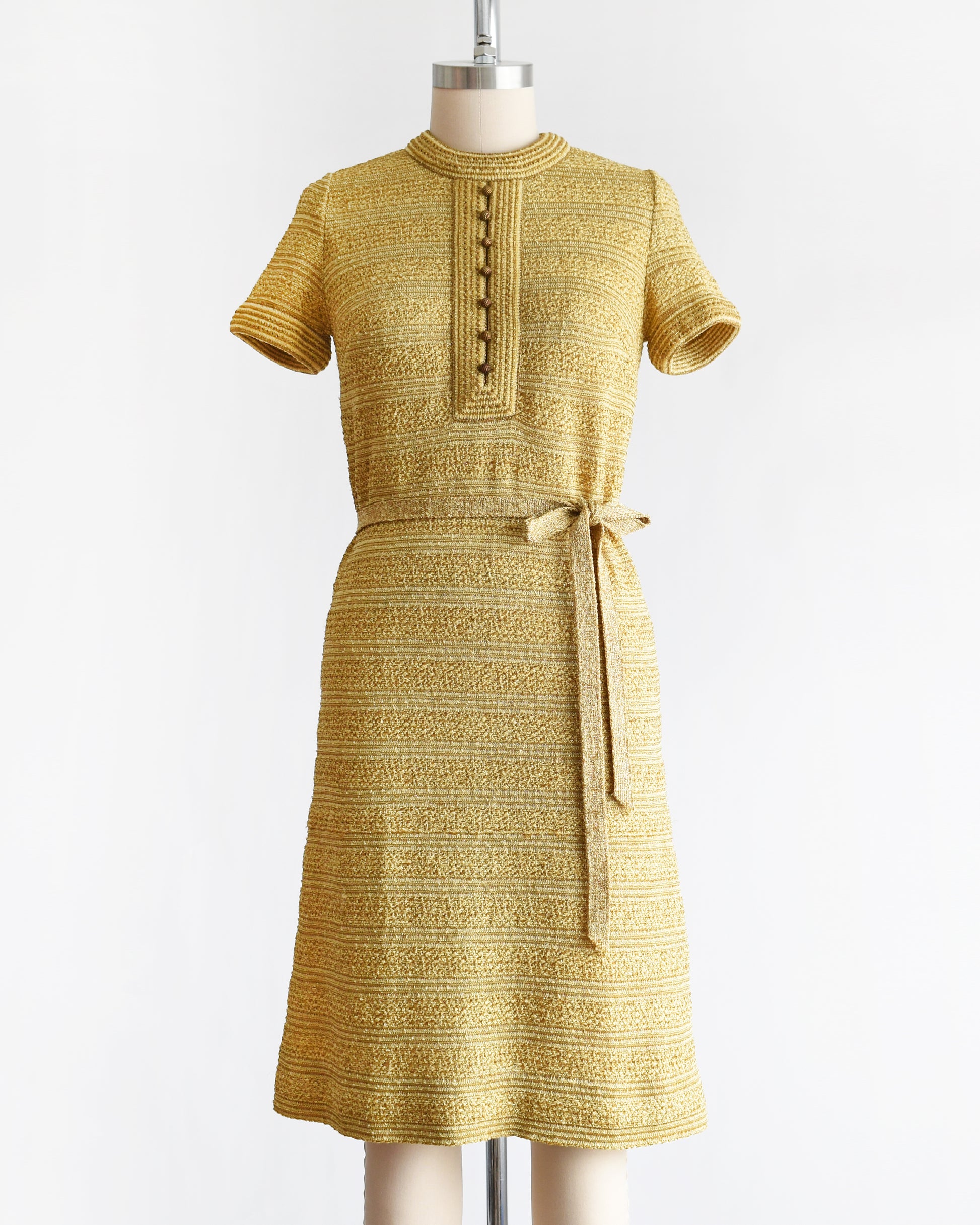 a vintage 1960s gold metallic dress on a mannequin against a white background