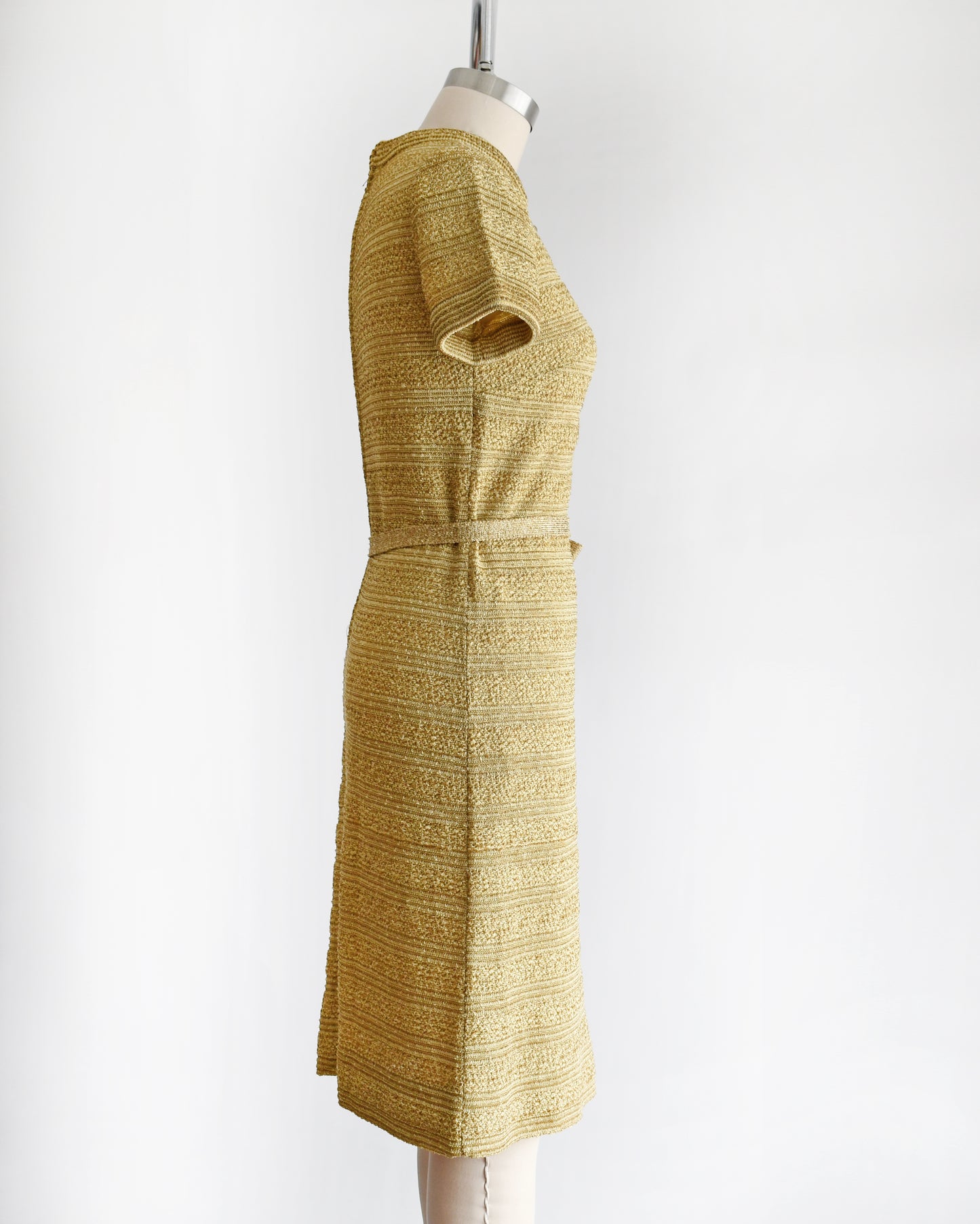 side view of a vintage 1960s gold metallic dress on a mannequin against a white background