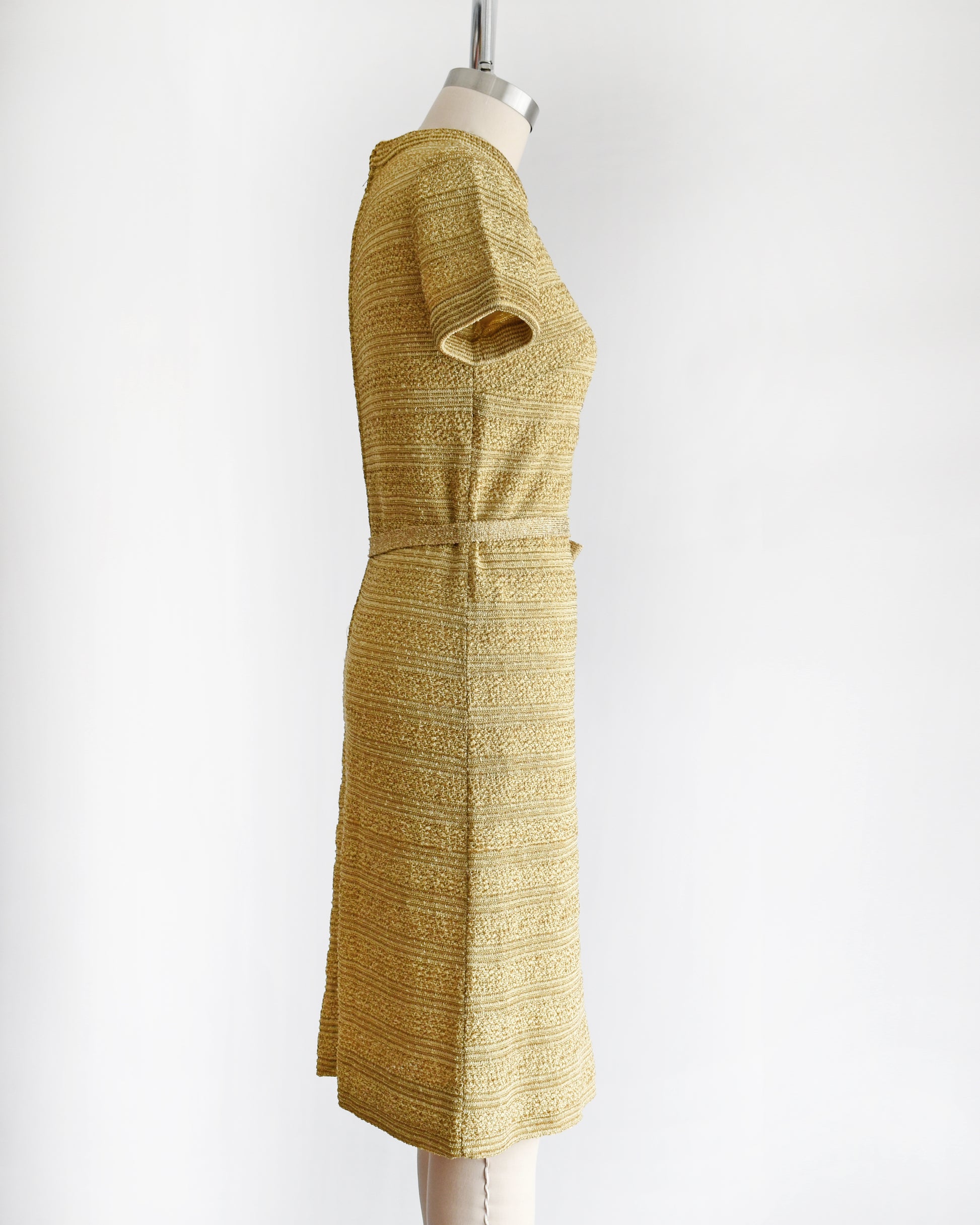 side view of a vintage 1960s gold metallic dress on a mannequin against a white background