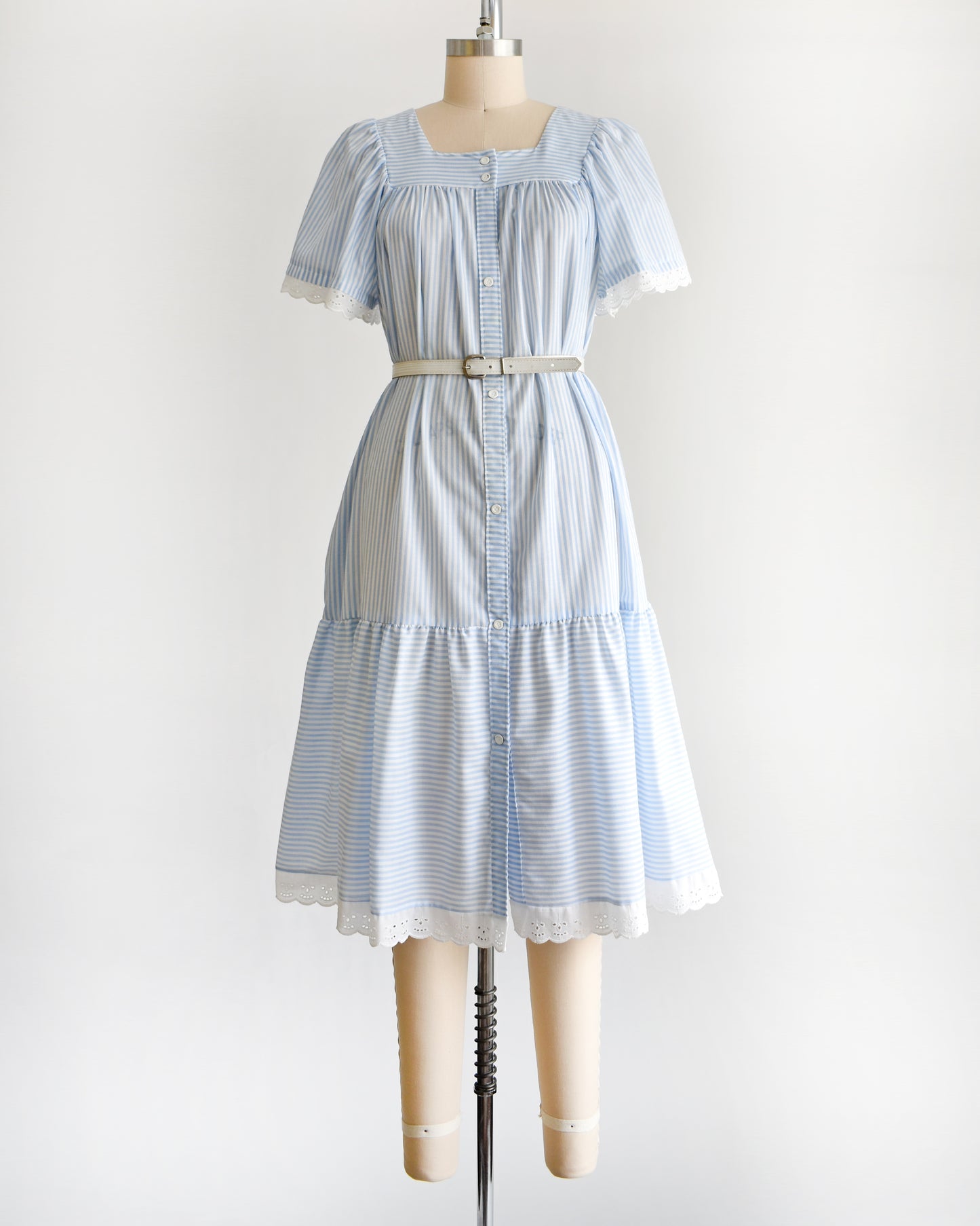 a vintage 1980s blue and white striped dress on a mannequin against a white background. The dress is shown with a belt, which is not included.