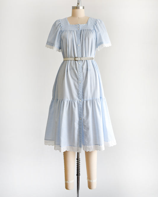 a vintage 1980s blue and white striped dress on a mannequin against a white background. The dress is shown with a belt, which is not included.