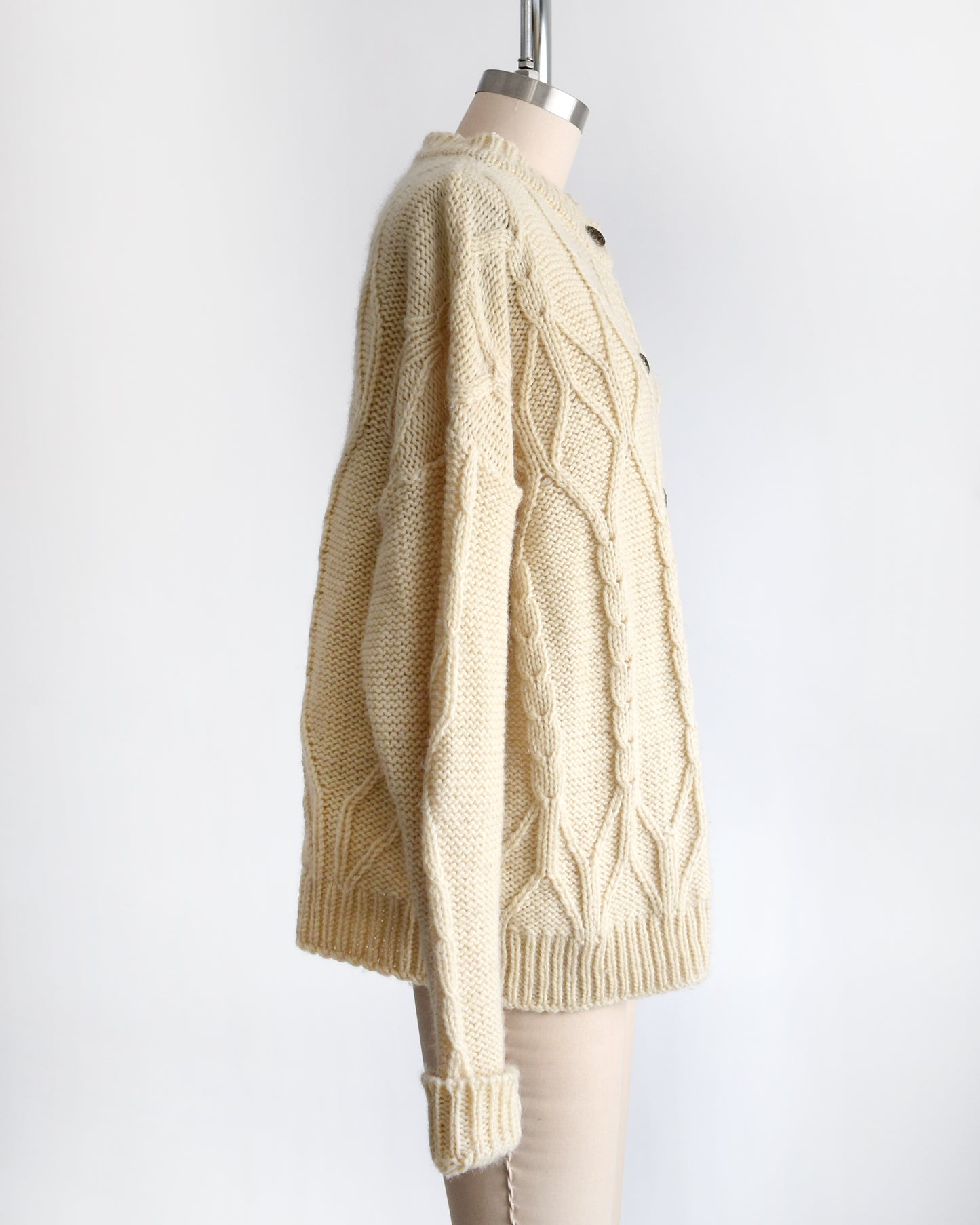 side view of a vintage 1990s cream cable knit wool cardigan