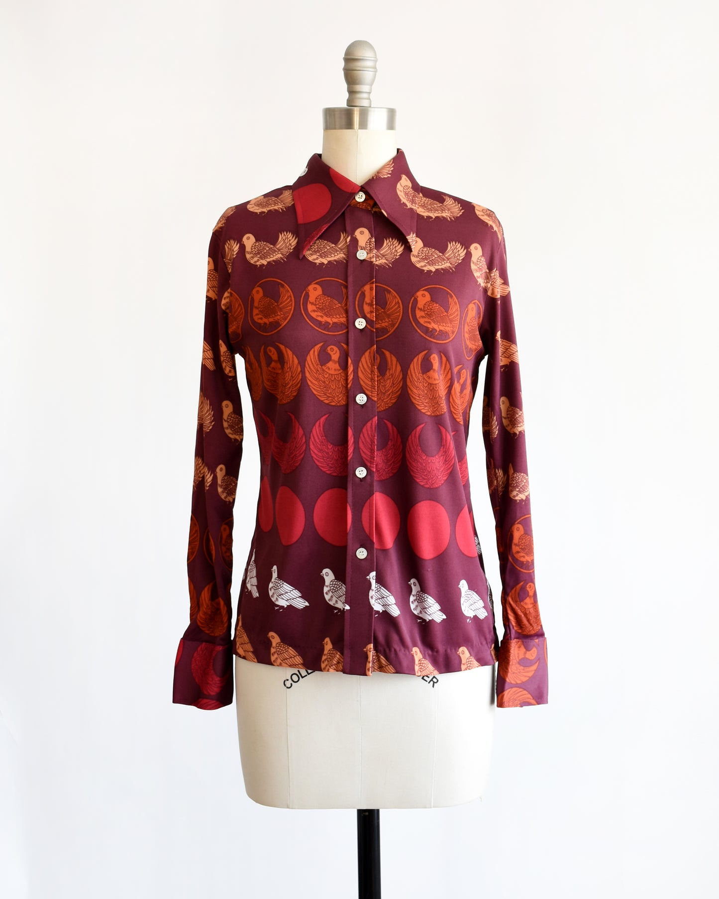 a vintage 1970s red patterned bird shirt on a mannequin against a white background