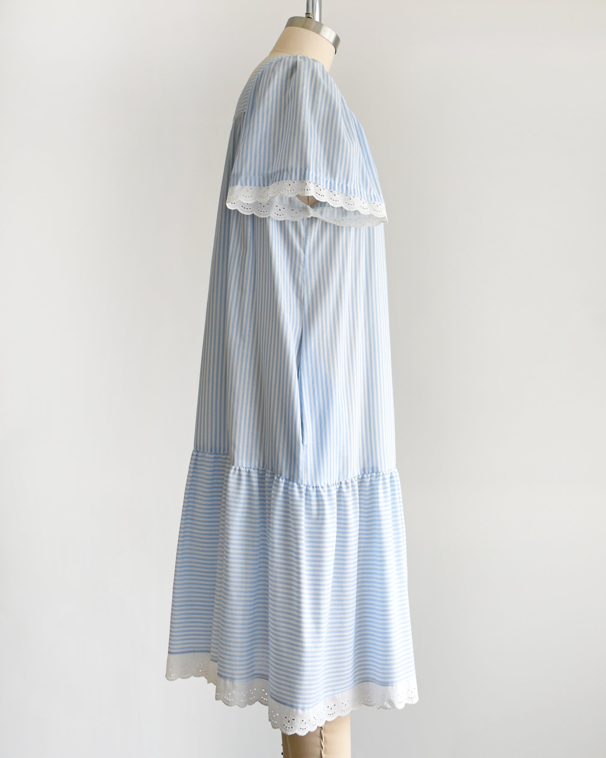 side view of a vintage 1980s blue and white striped dress on a mannequin against a white background. 