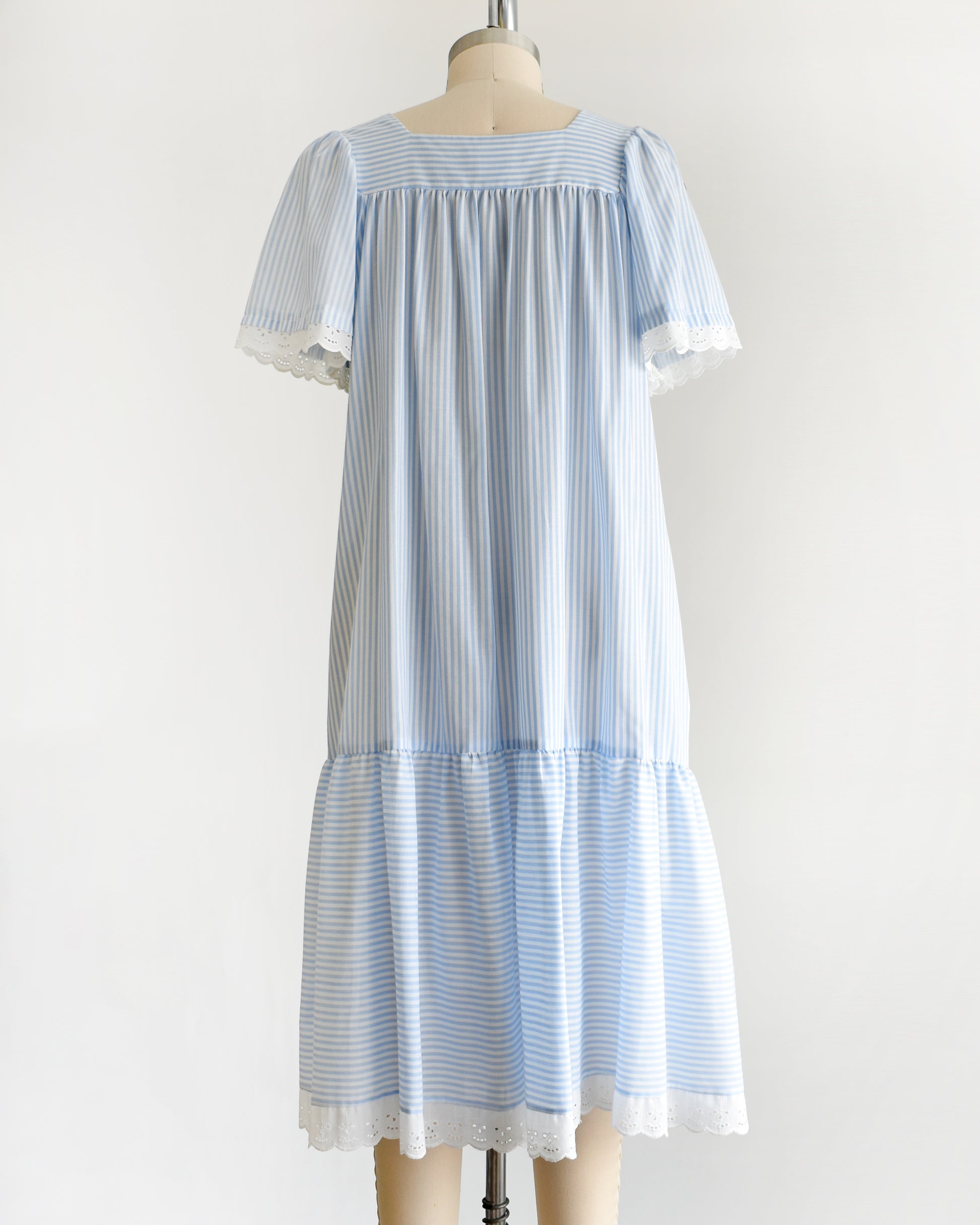 back view of a vintage 1980s blue and white striped dress on a mannequin against a white background.