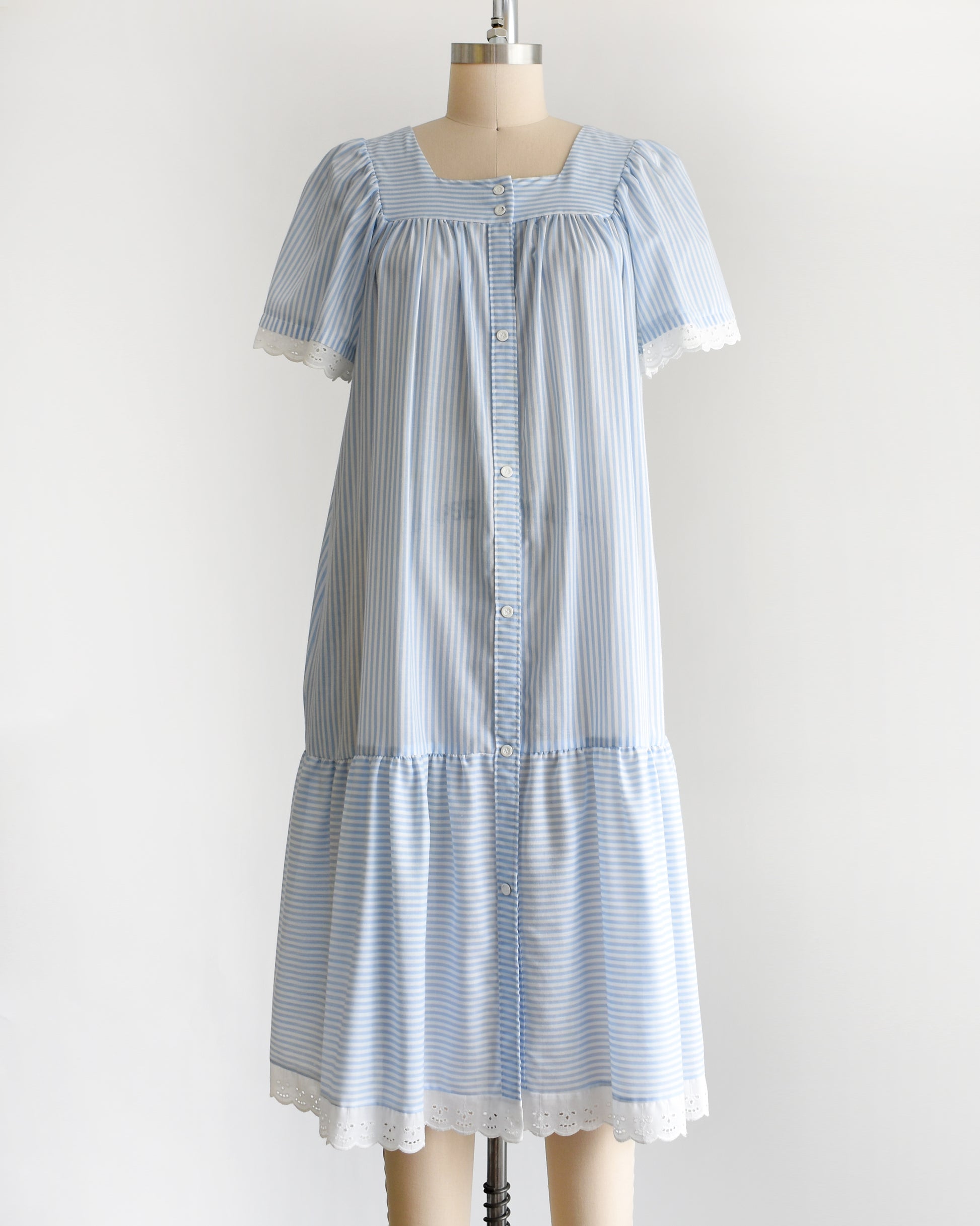 side view of a vintage 1980s blue and white striped dress on a mannequin against a white background
