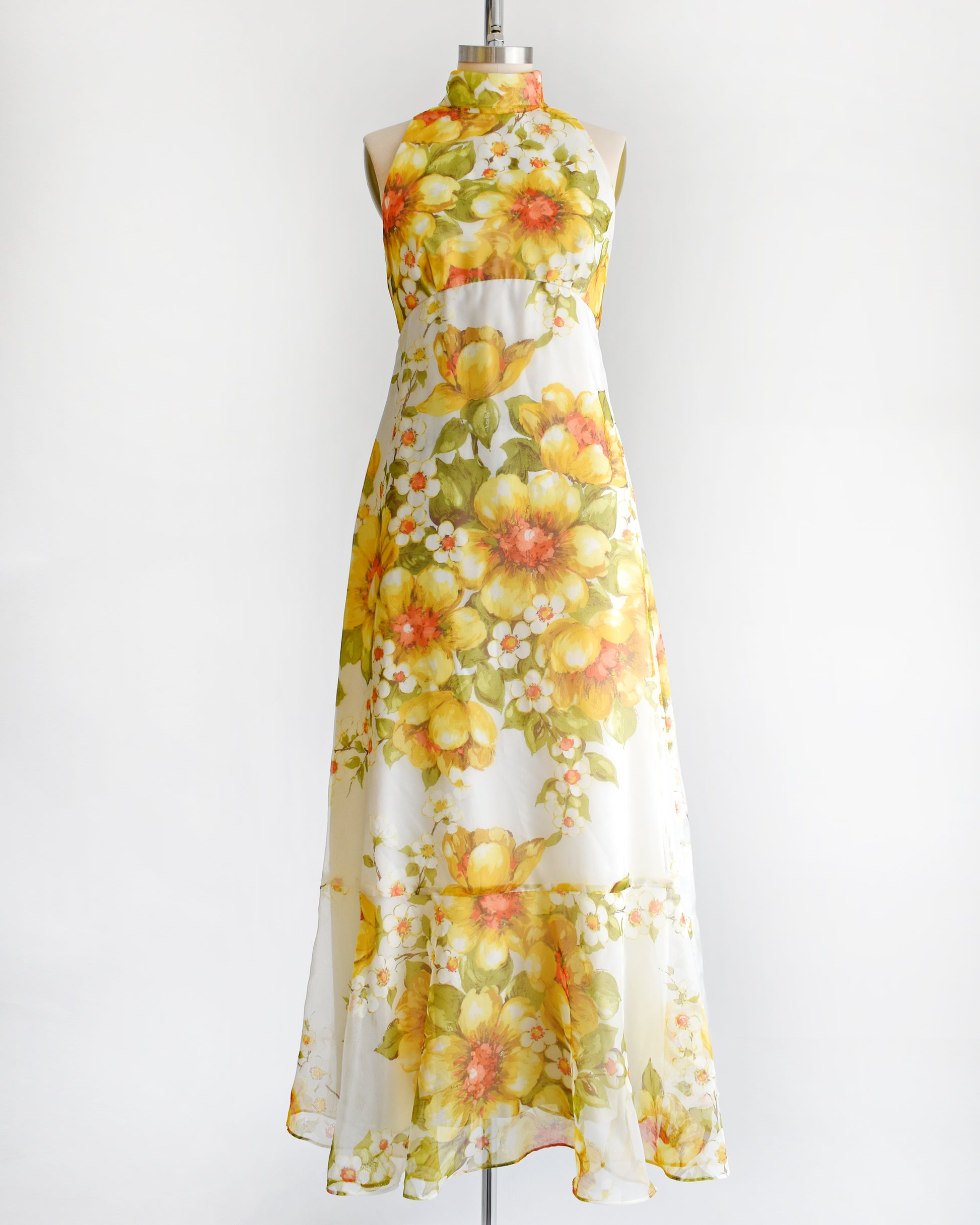 a vintage 1970s yellow and white floral dress on a mannequin against a white background