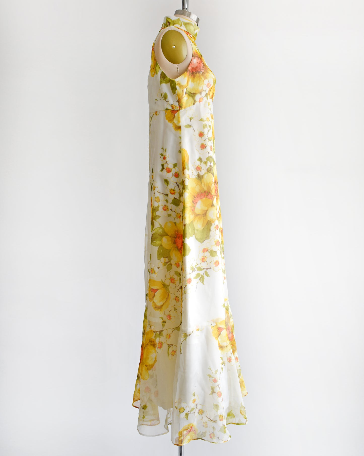 side view of a vintage 1970s yellow and white floral dress on a mannequin against a white background