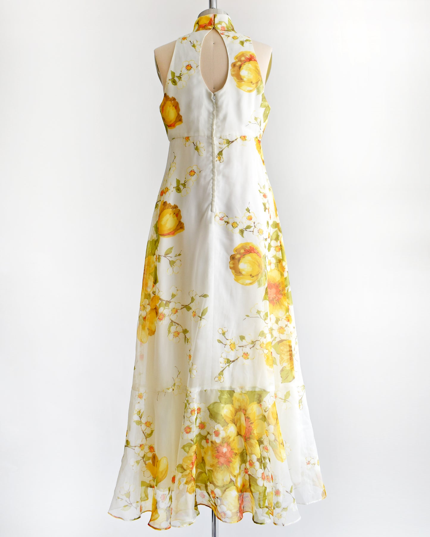 back view of a vintage 1970s yellow and white floral dress on a mannequin against a white background