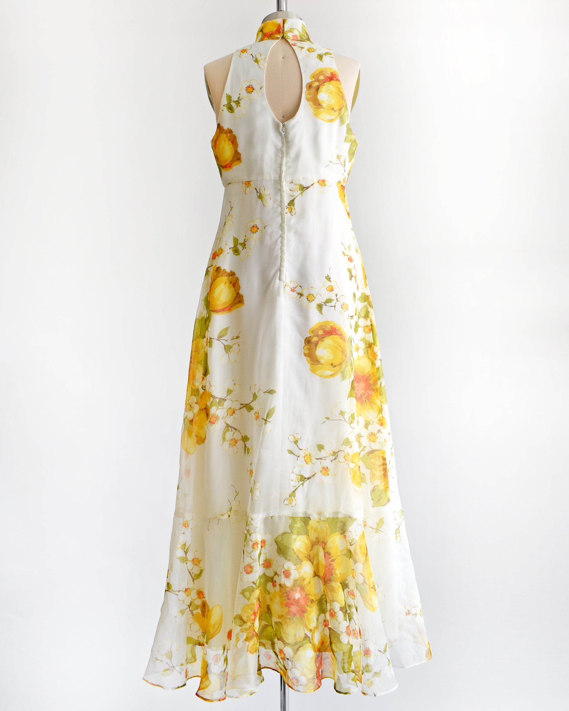 back view of a vintage 1970s yellow and white floral dress on a mannequin against a white background