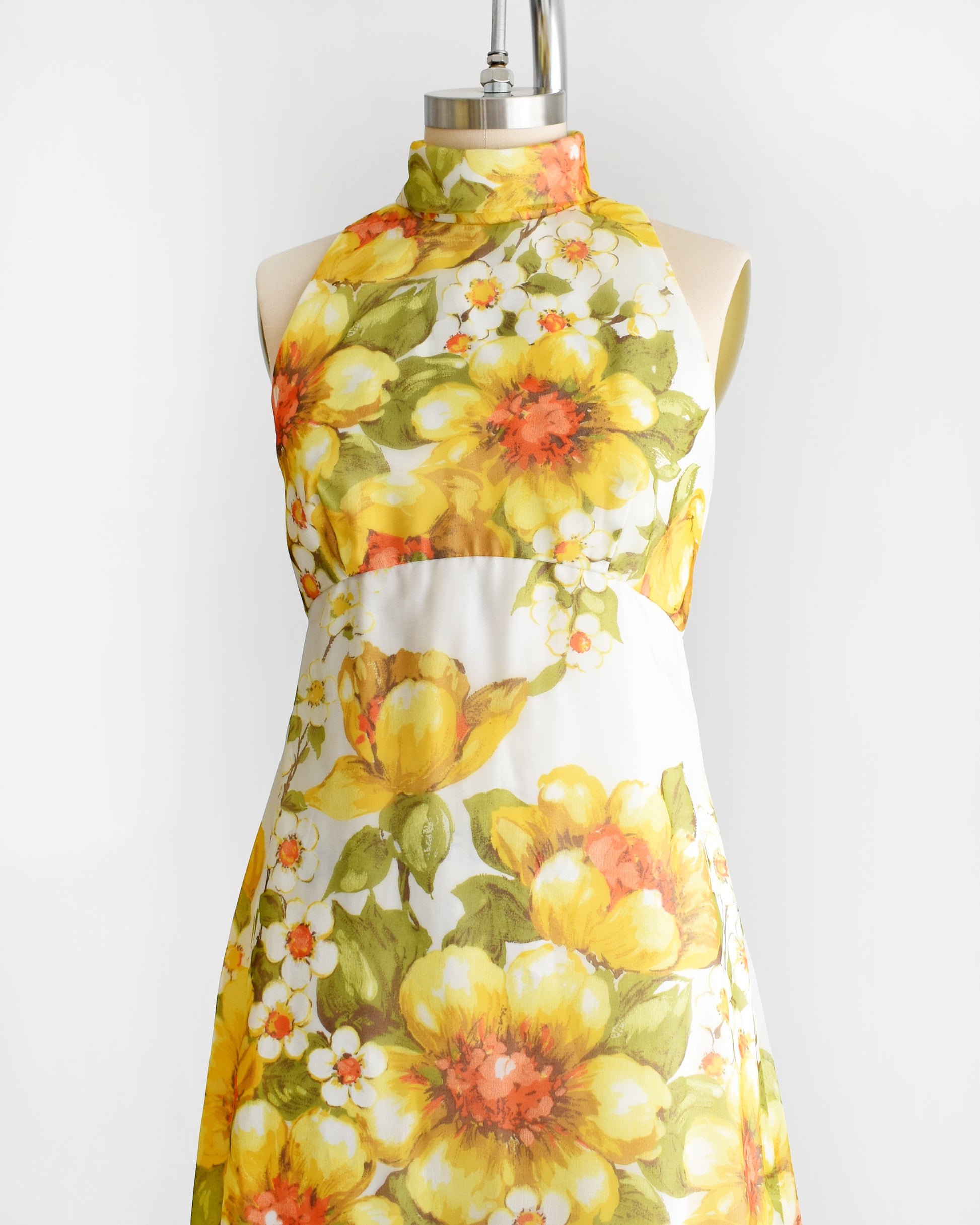 side front view of a vintage 1970s yellow and white floral dress on a mannequin against a white background