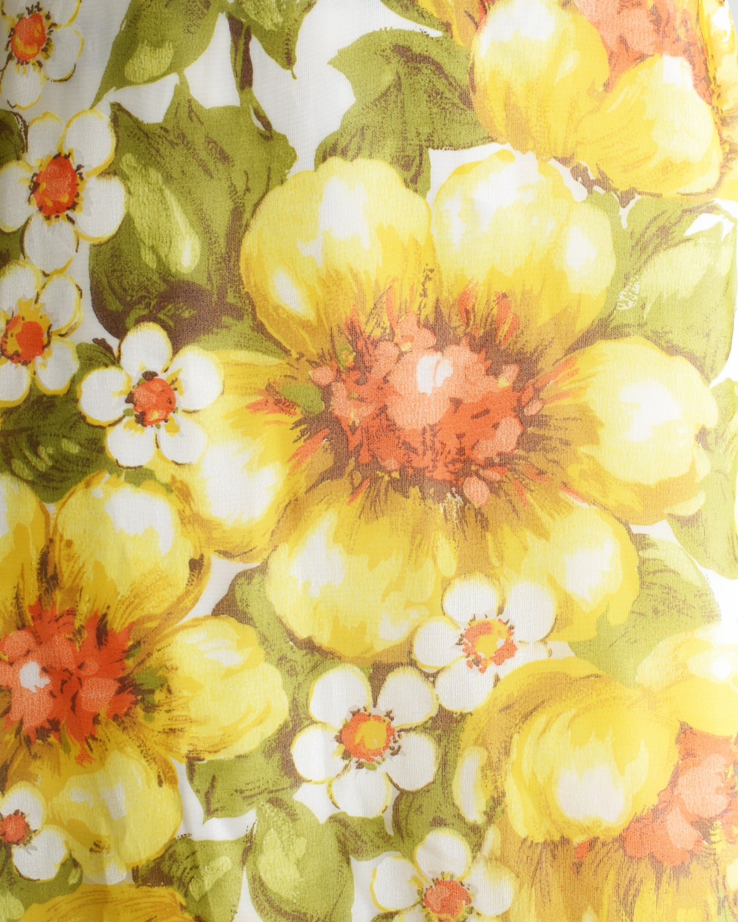 Close-up of a floral pattern with yellow, orange, and white flowers on a green background.