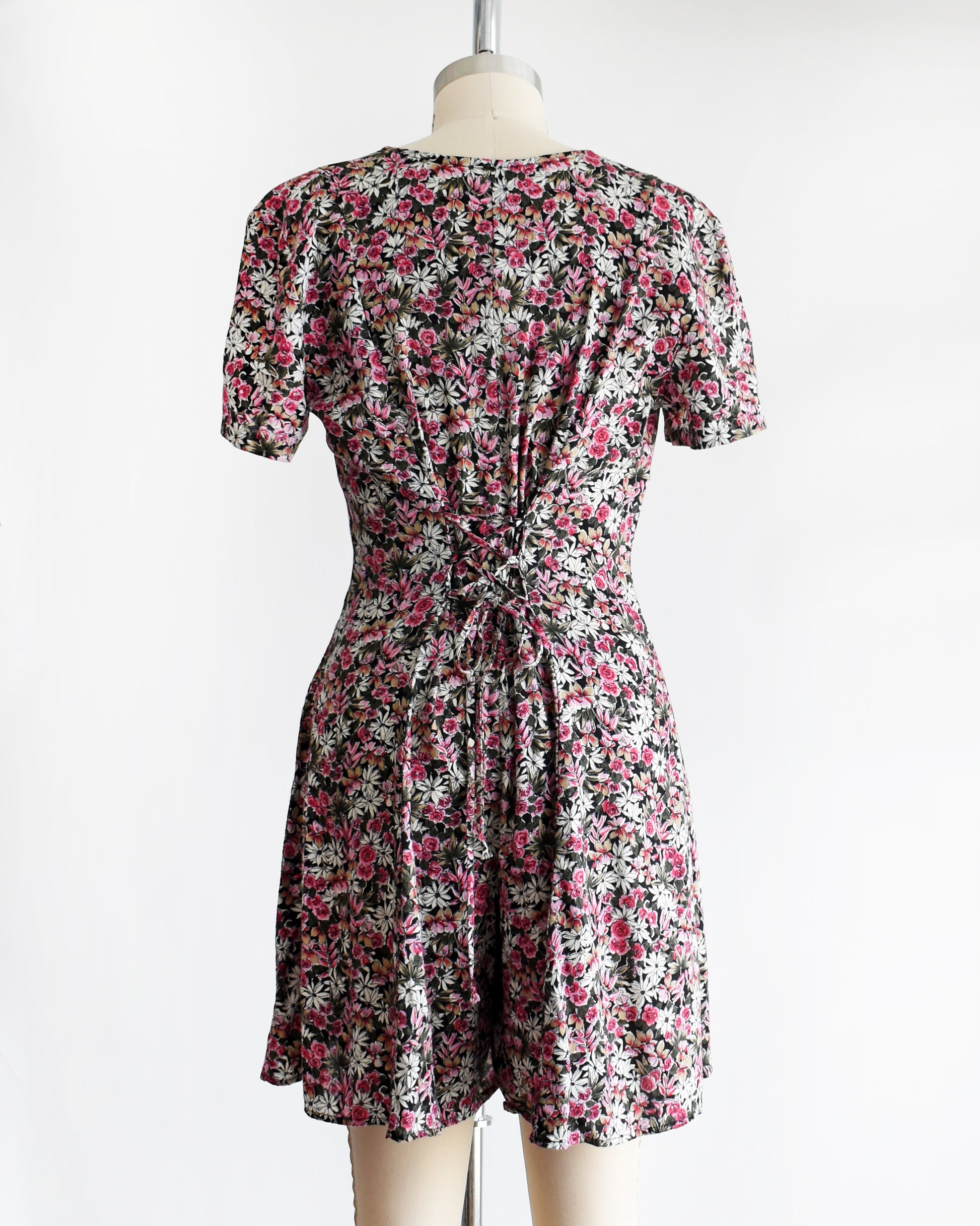 back view of a vintage 1990s floral romper  with  lace up back on a mannequin against a white background