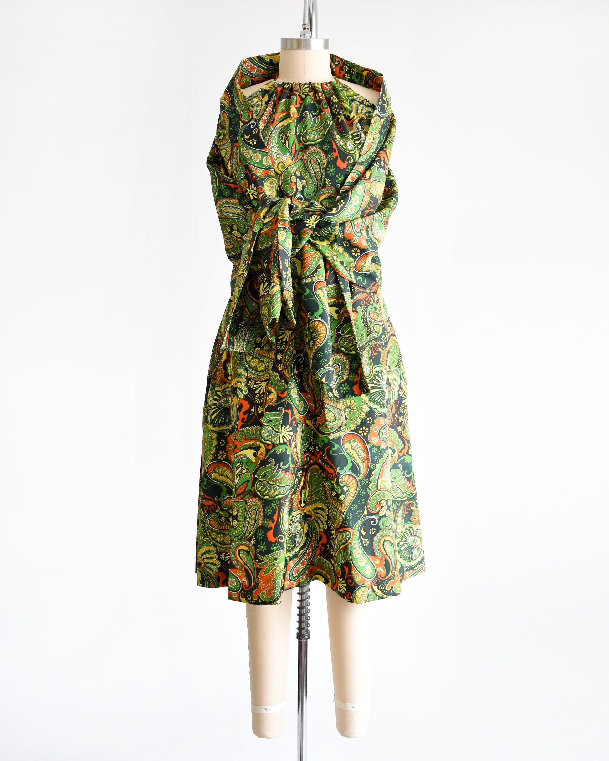 A vintage 1970s psychedelic paisley dress with matching shawl on a mannequin against a white background