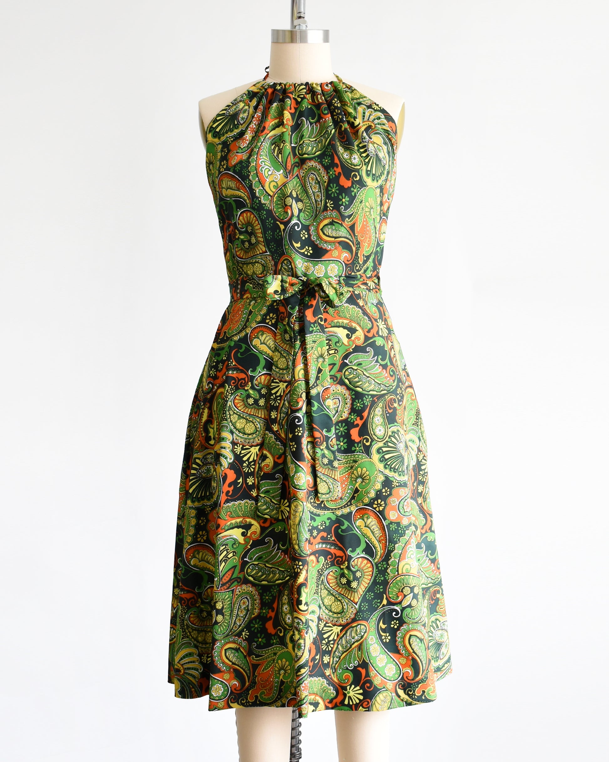 A vintage 1970s psychedelic paisley dress  on a mannequin against a white background