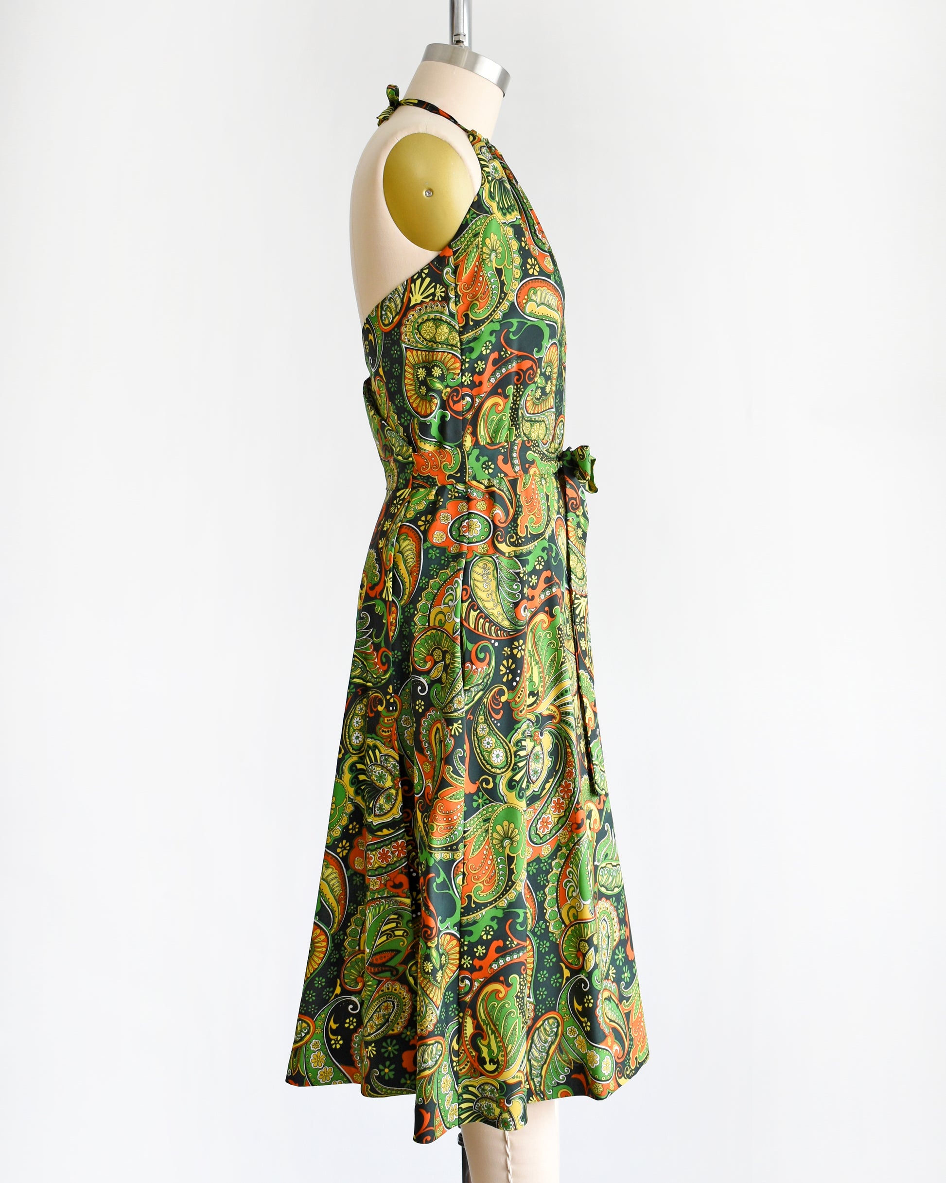 side view of a vintage 1970s psychedelic paisley dress  on a mannequin against a white background