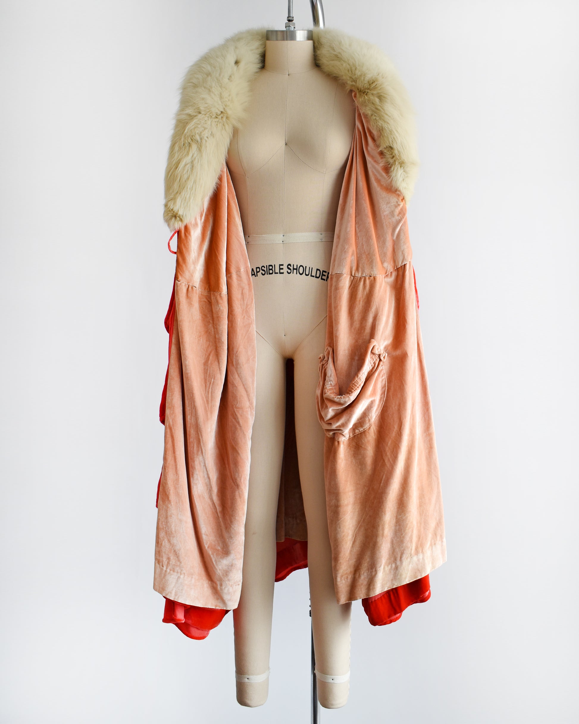 A vintage 1920s ruffled silk velvet opera coat with cream fox fur trim. The cape is open showing the peach lining and one of the inside pockets