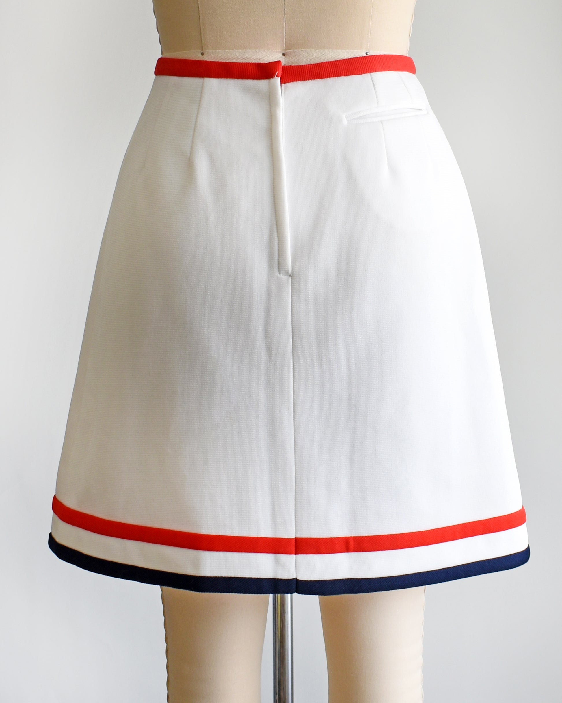 back view of a vintage 1970s white skort with red and navy trim on a dress form against a white background