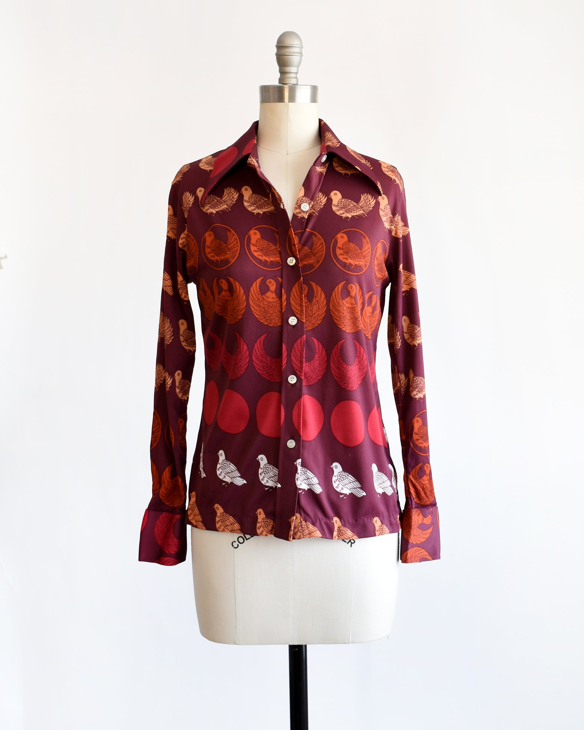 a vintage 1970s red patterned bird shirt on a mannequin against a white background/ the top two buttons are unbuttoned in this photo.