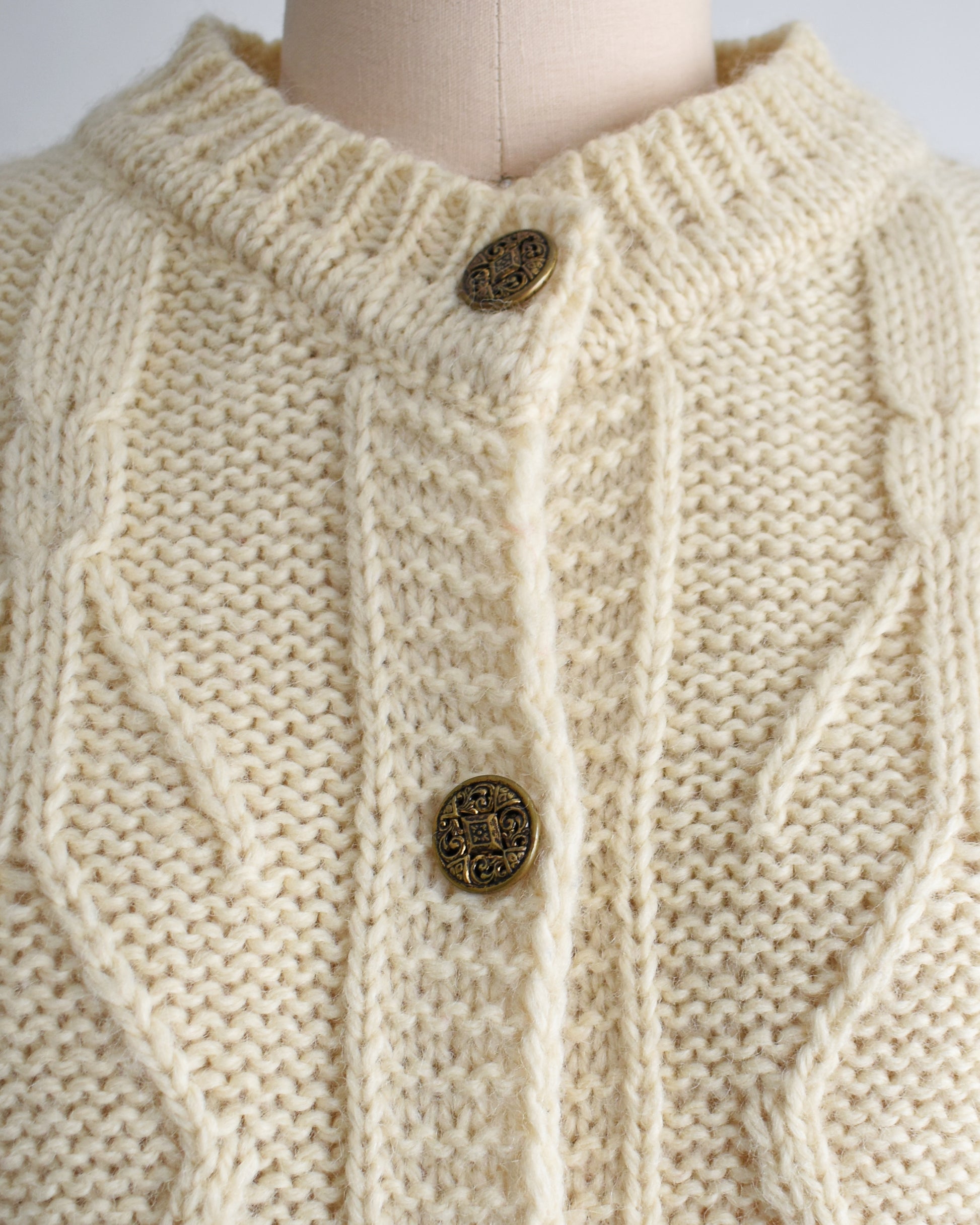 close up of the gold tone buttons on a vintage 1990s cream cable knit wool cardigan