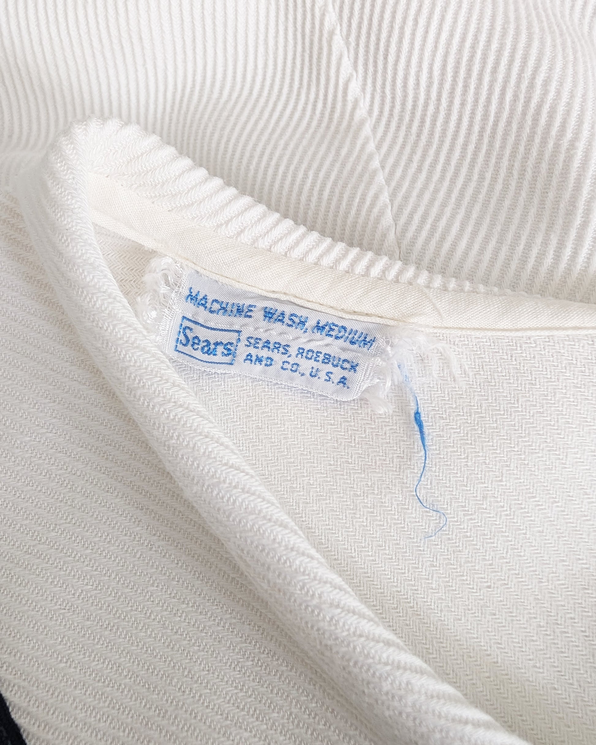 Close-up of a white garment with a Sears label on a white background