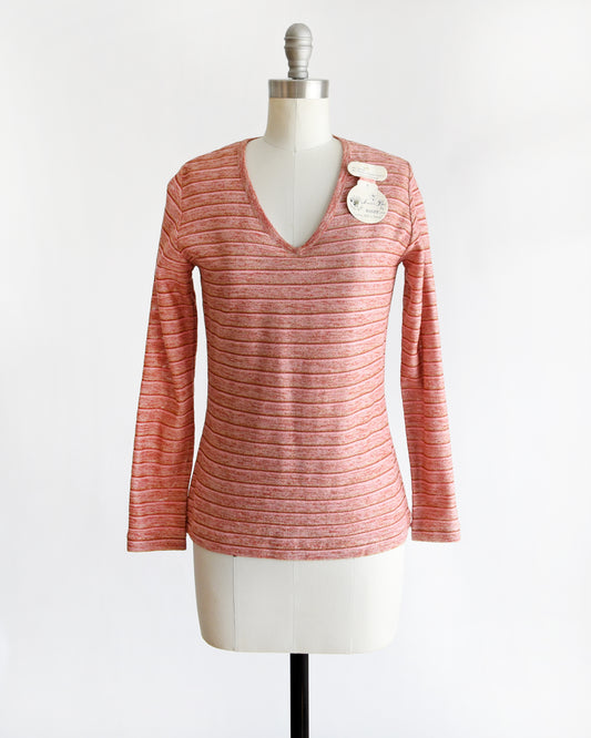 a vintage 1970s pink long-sleeve top on a mannequin with a white background