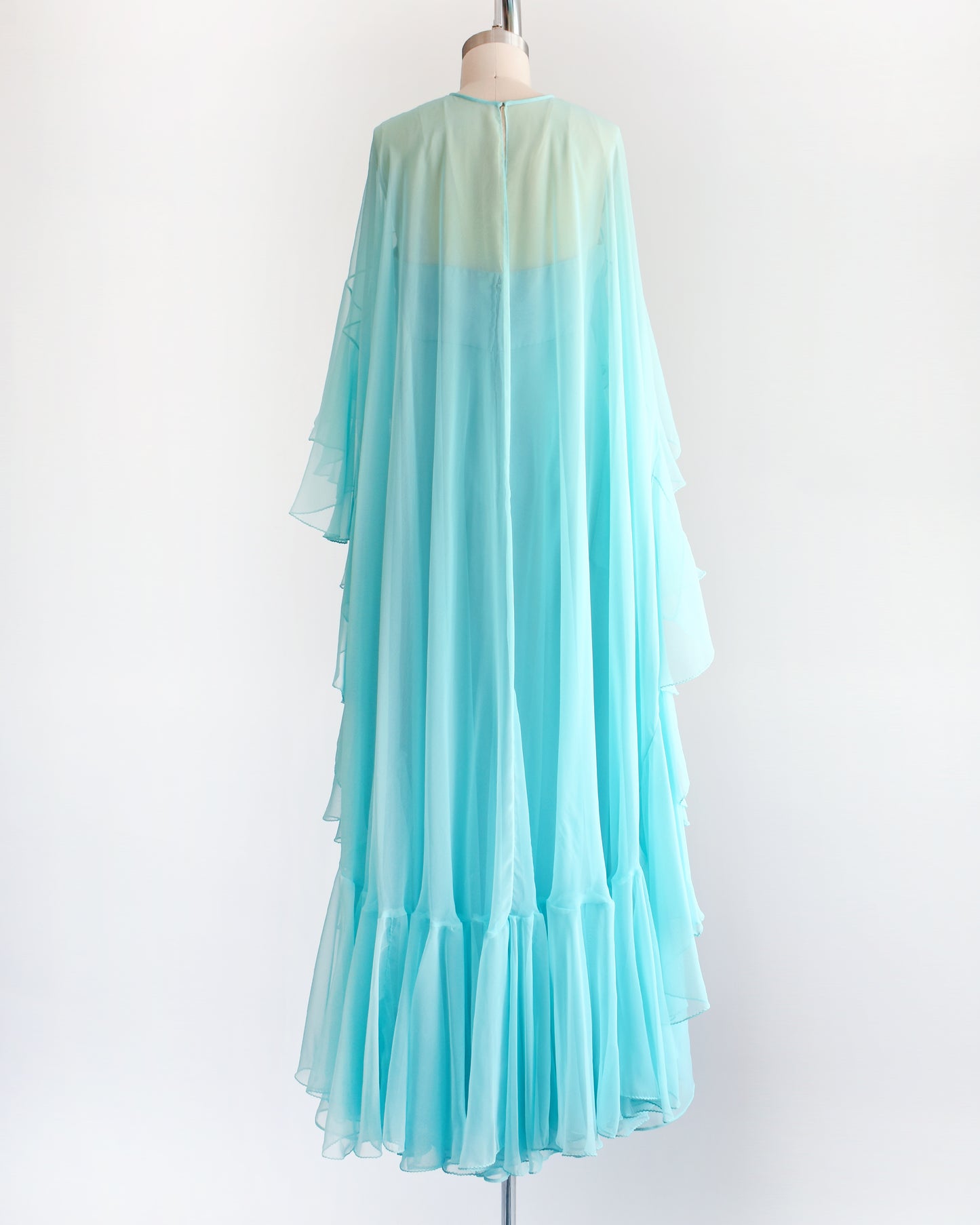 back view of a vintage 1960s light blue ruffled maxi dress on a mannequin against a white background