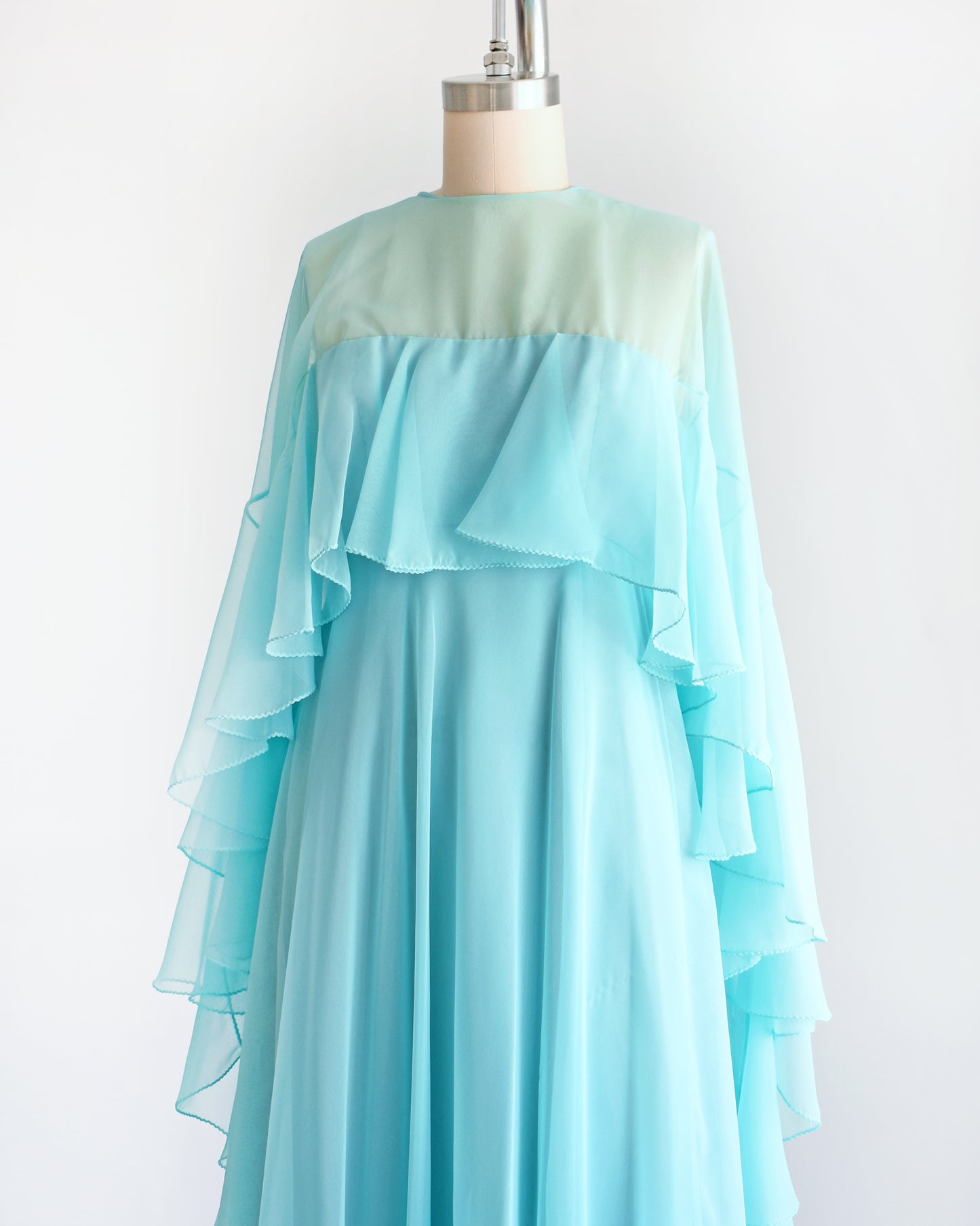 side front view of a vintage 1960s light blue ruffled maxi dress on a mannequin against a white background