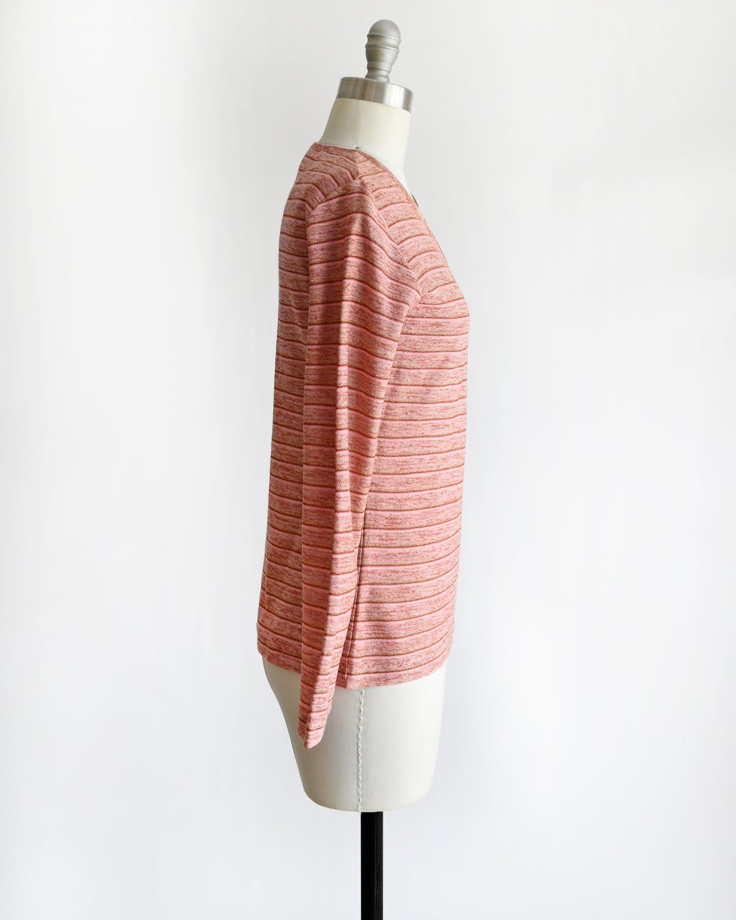 side view of a vintage 1970s pink long-sleeve top on a mannequin with a white background