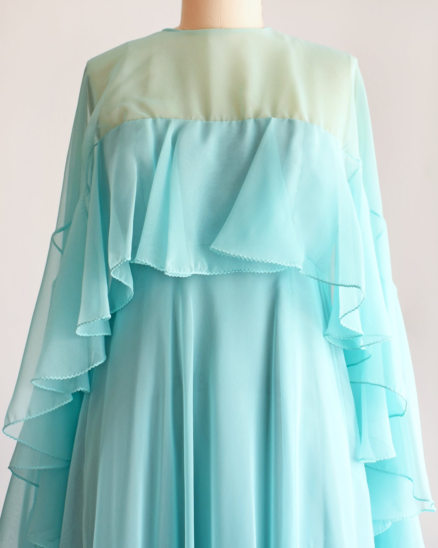 close up of the bodice of a vintage 1960s light blue ruffled maxi dress on a mannequin against a white background