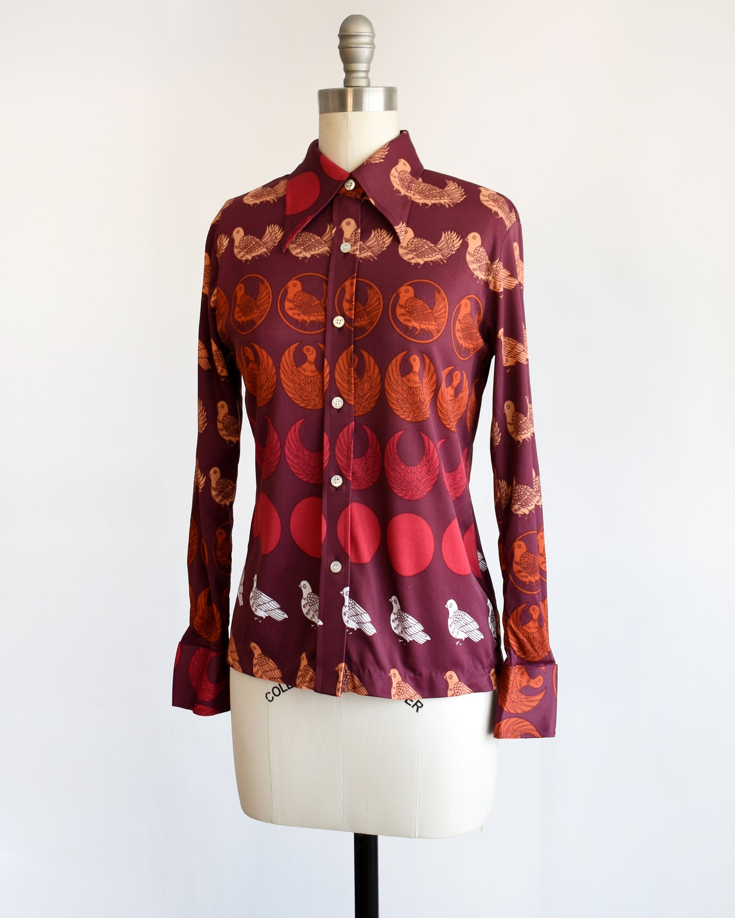 side front view of a vintage 1970s red patterned bird shirt on a mannequin against a white background