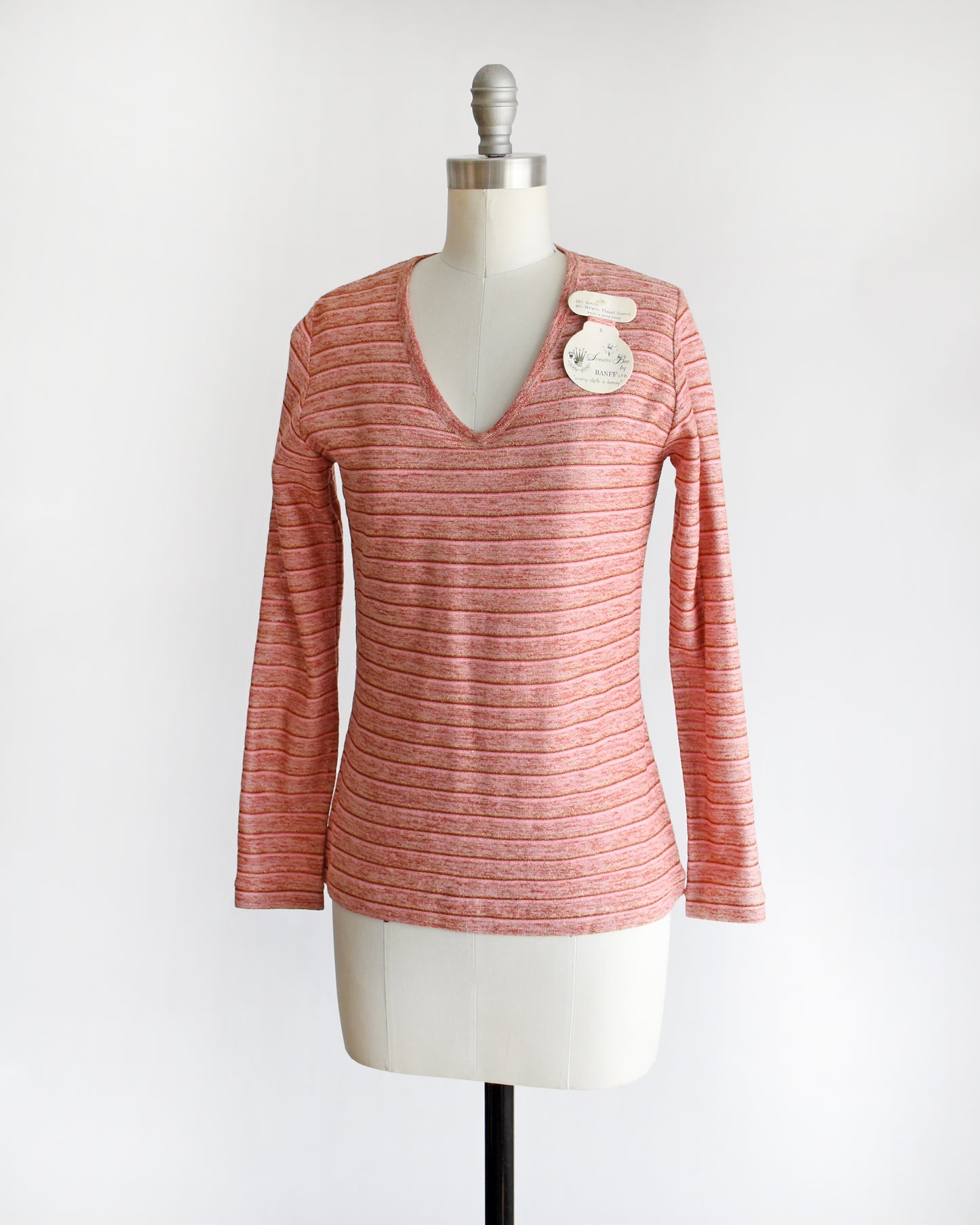 side front view of a vintage 1970s pink long-sleeve top on a mannequin with a white background