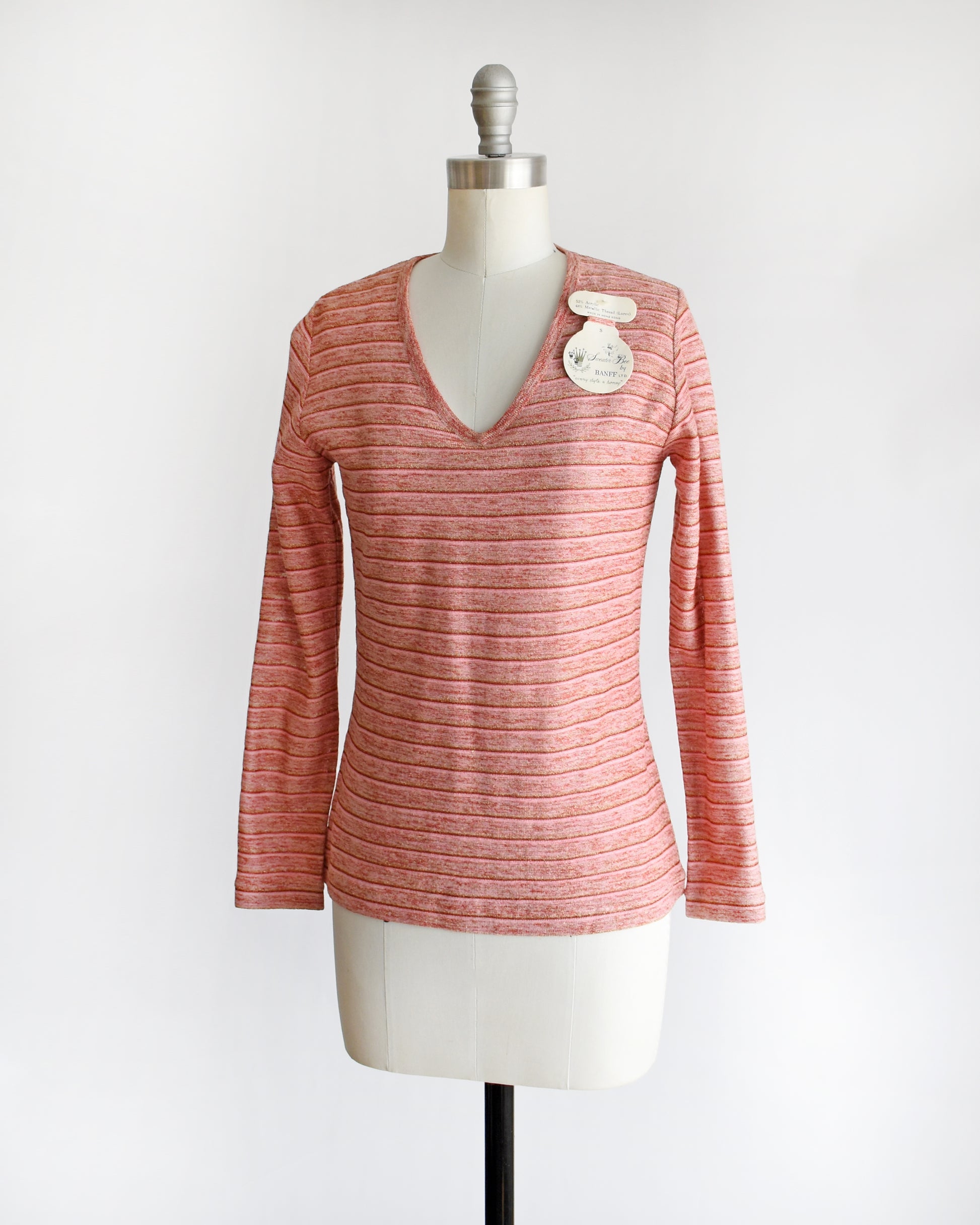 side front view of a vintage 1970s pink long-sleeve top on a mannequin with a white background