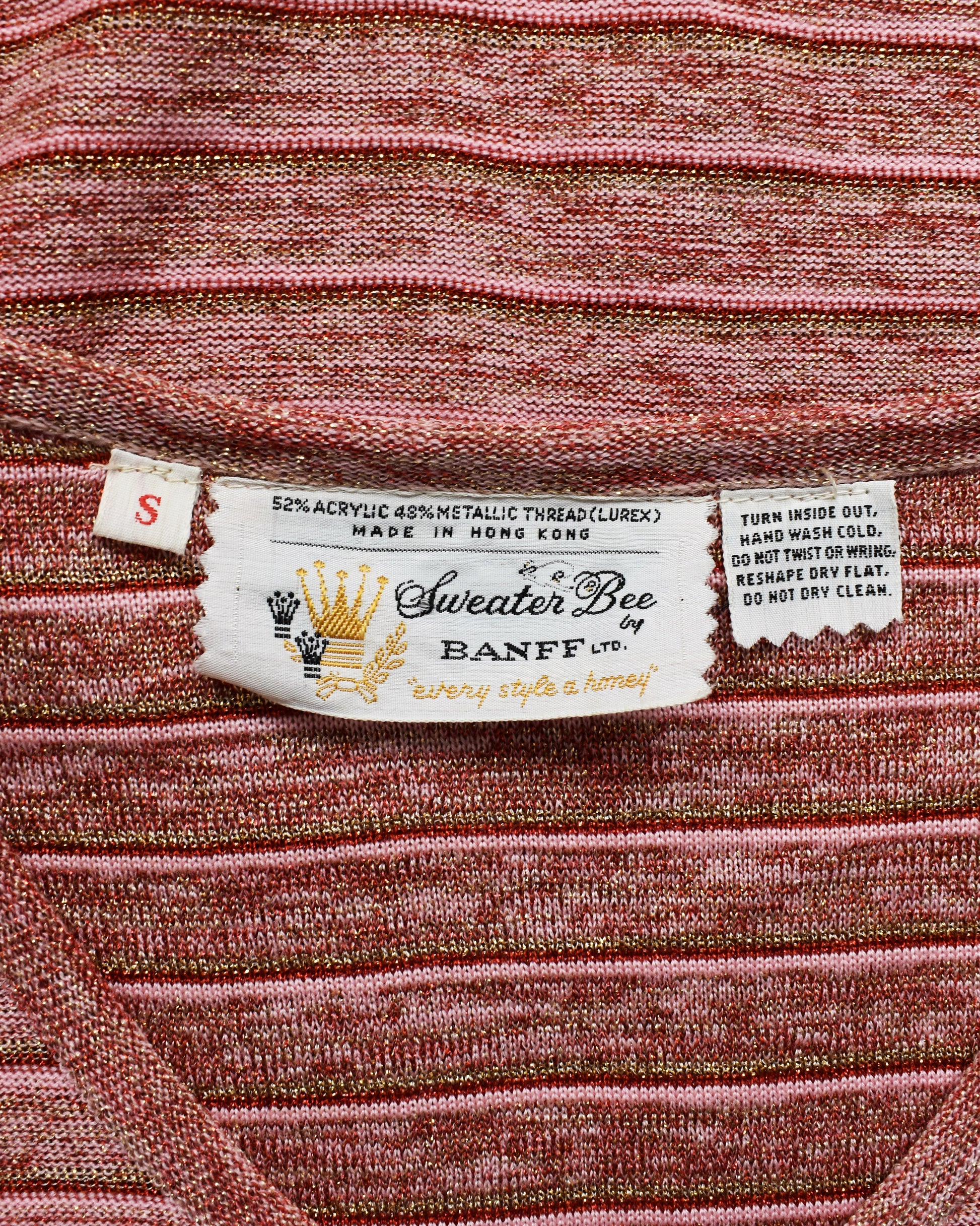 Close-up of a label on a textured pink sweater with 'Sweater Bee Banff' branding.