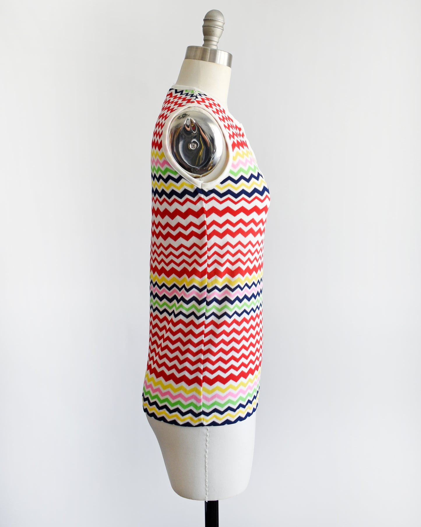 side view of a vintage 1970s colorful zigzag patterned sleeveless top on a mannequin against a white background