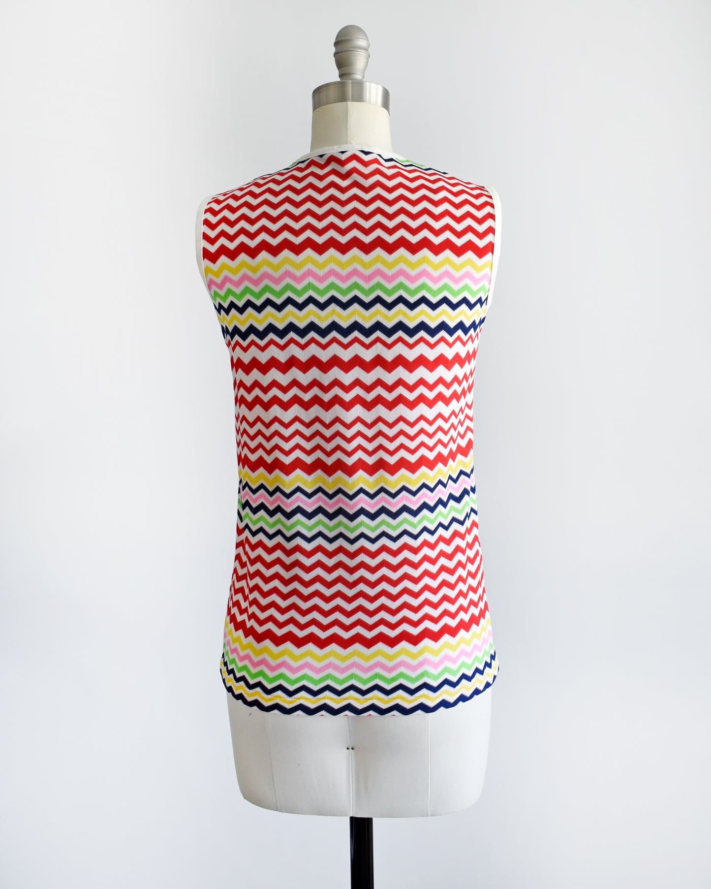 back view of a vintage 1970s colorful zigzag patterned sleeveless top on a mannequin against a white background
