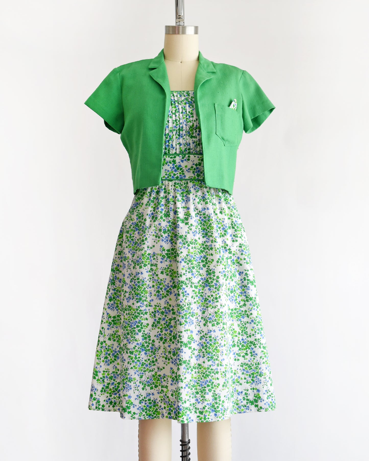 a vintage 1970s green floral dress with green bolero on a mannequin against a white background