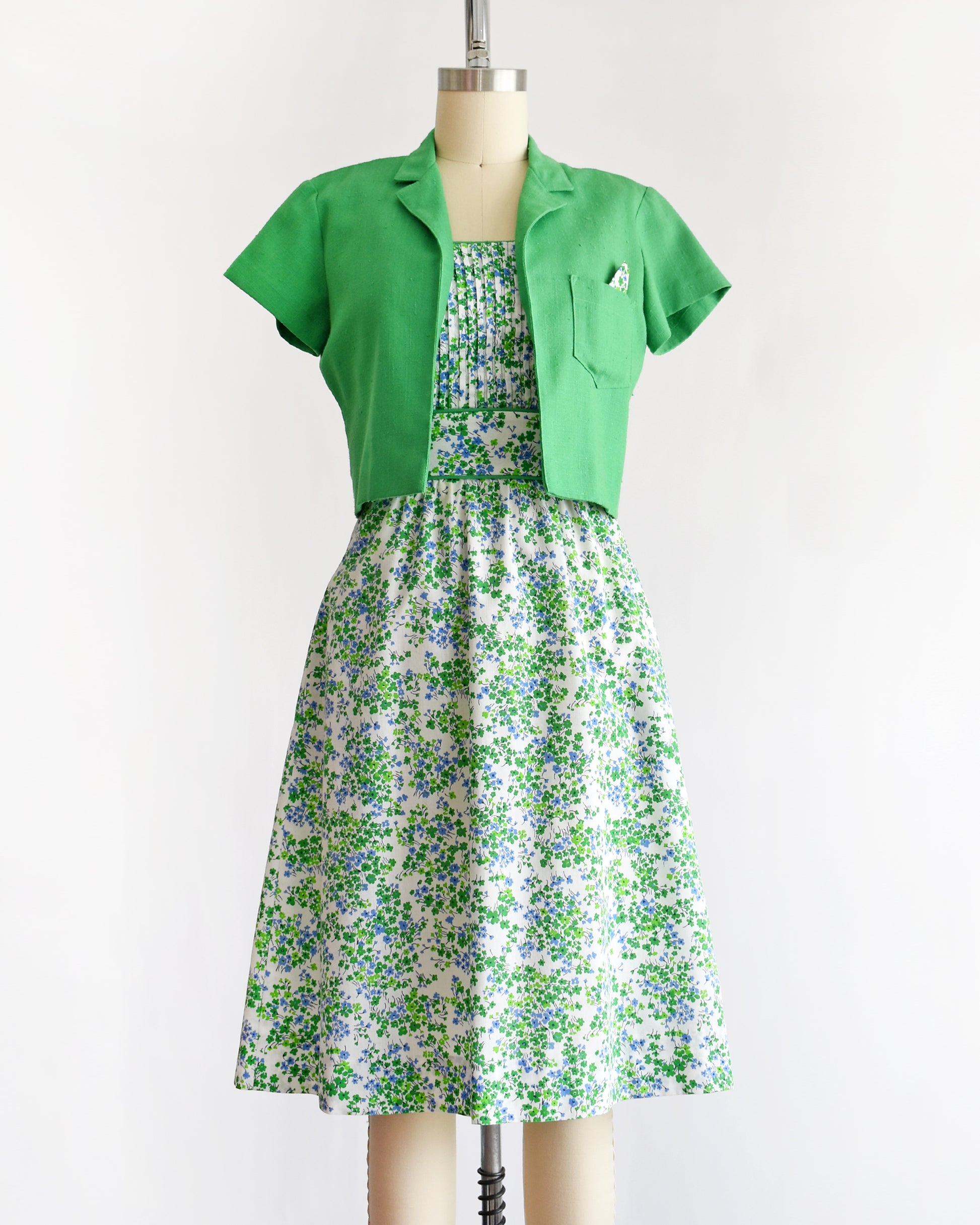 a vintage 1970s green floral dress with green bolero on a mannequin against a white background
