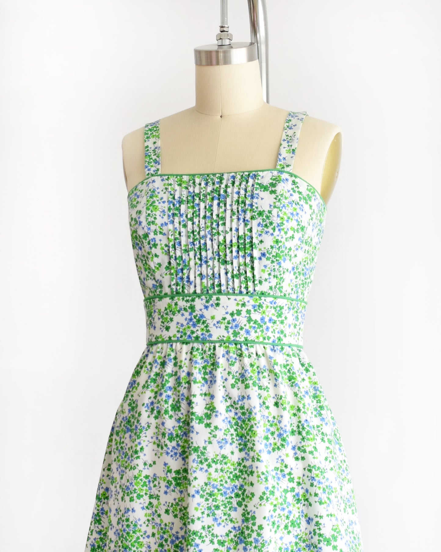 a vintage 1970s green floral dress on a mannequin against a white background