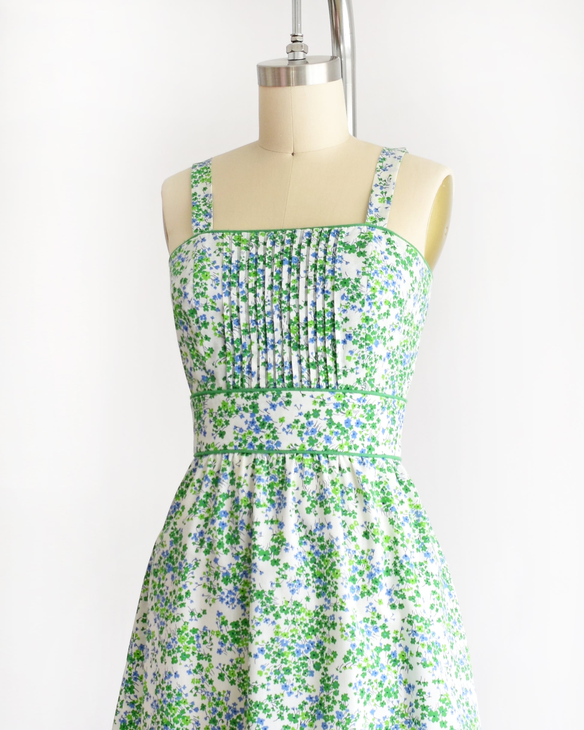 a vintage 1970s green floral dress on a mannequin against a white background