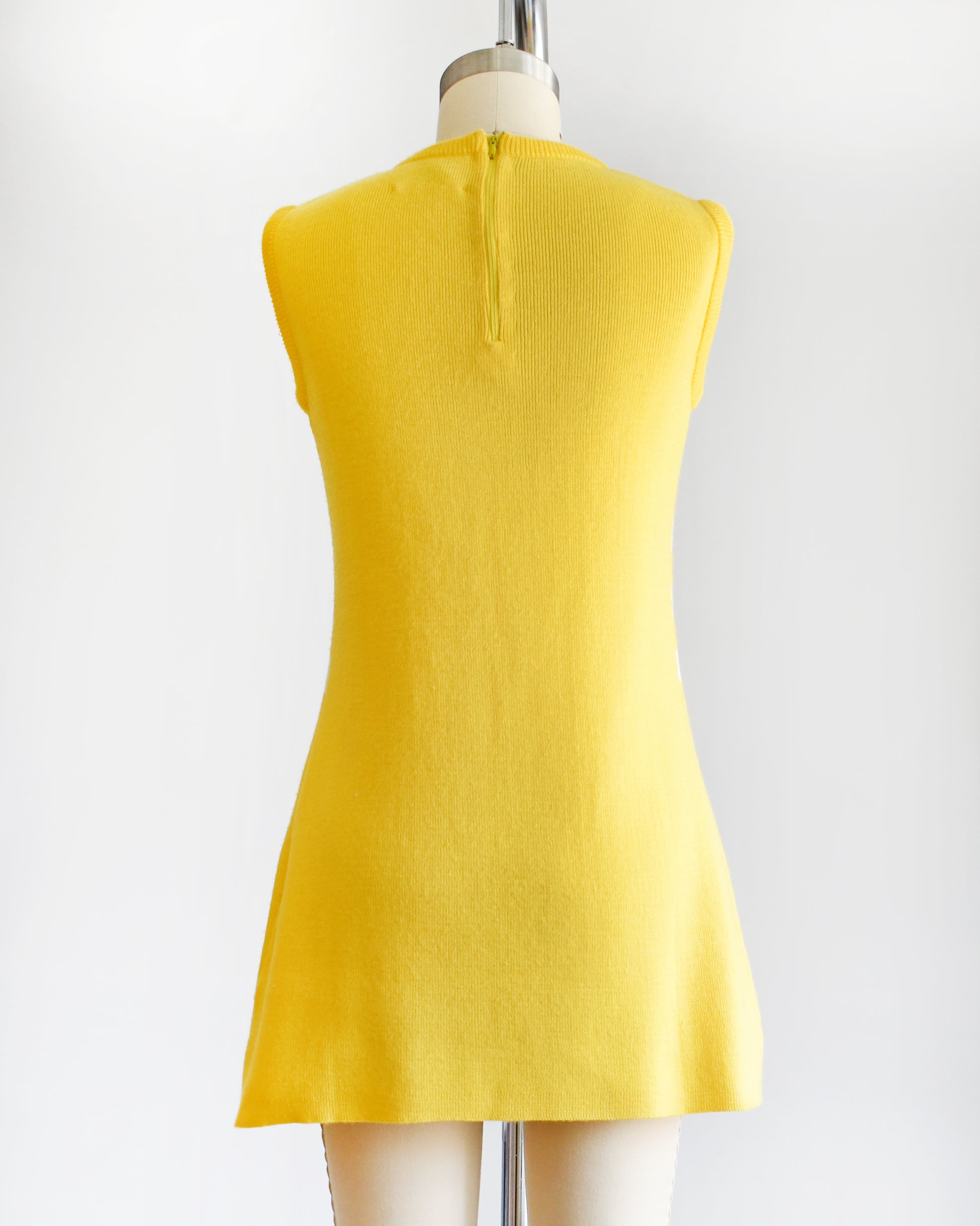 back view of a vintage 1970s yellow dress with floral design on a mannequin against a white background