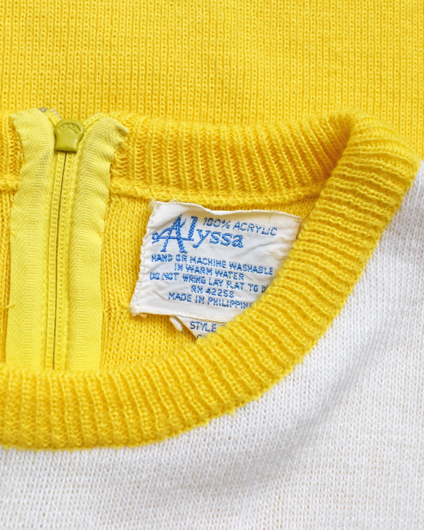Close-up of a yellow garment with a label reading 'Alyssa' on a white background.