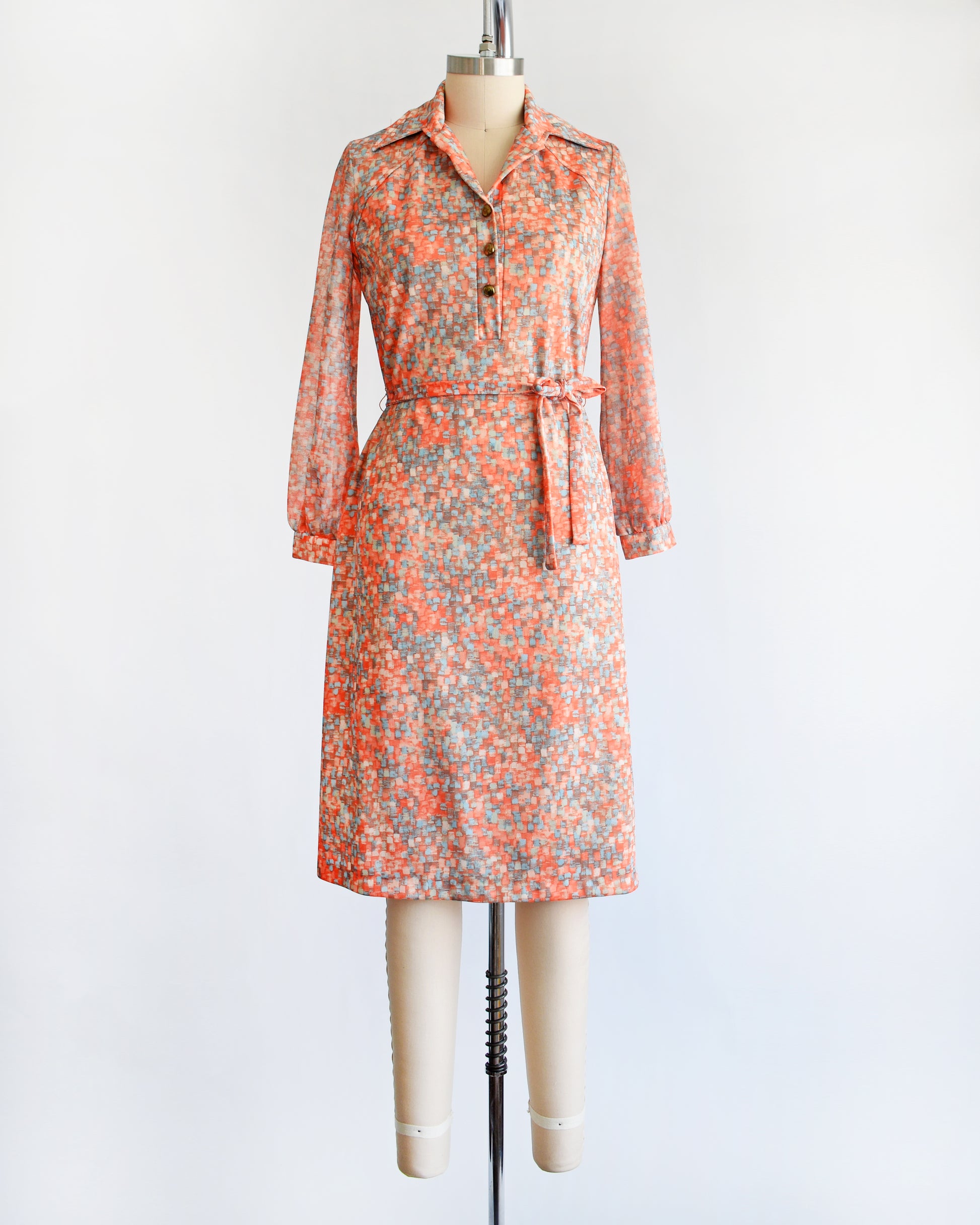 a vintage 1970s orange and blue dress on a mannequin against a white background
