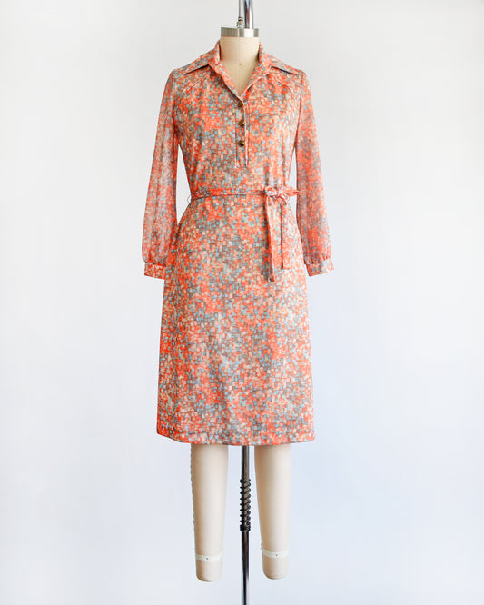 a vintage 1970s orange and blue dress on a mannequin against a white background