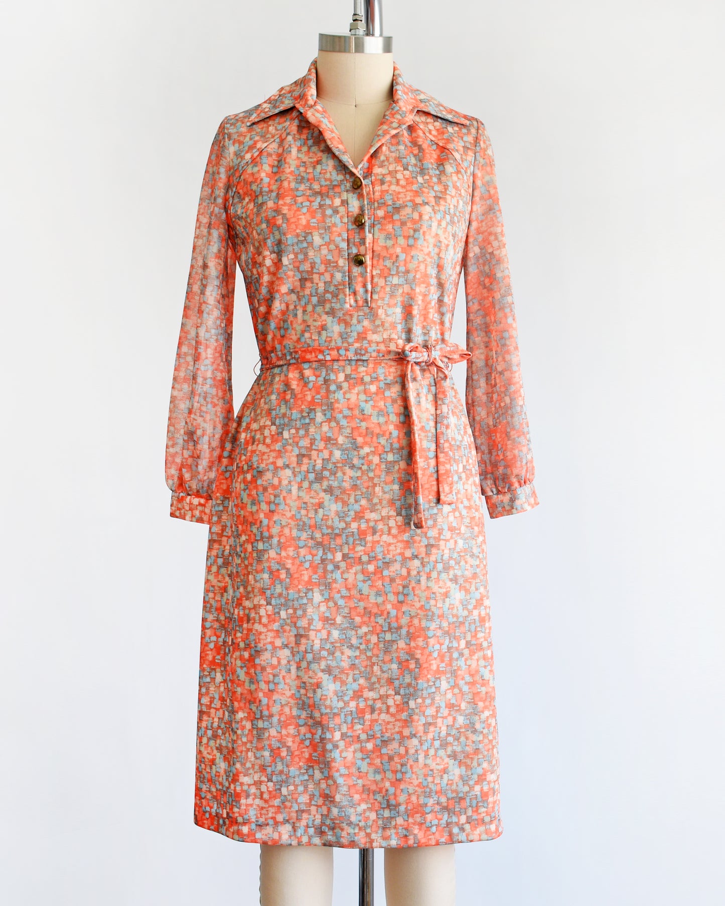 a vintage 1970s orange and blue dress on a mannequin against a white background